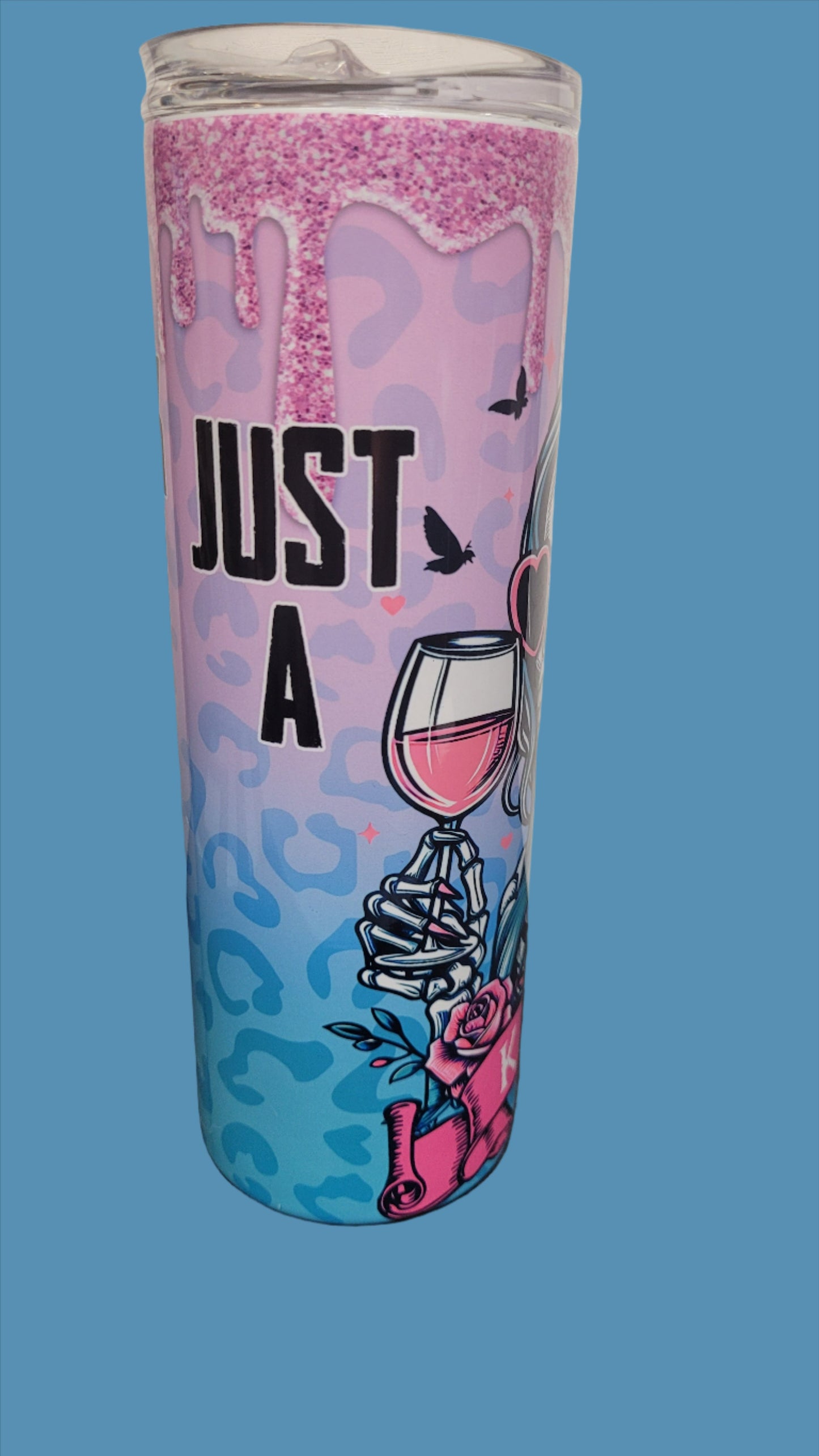 Just A Hawk Tuak Kinda Girl. Featuring a wine sipping skeleton gal surrounded by pink roses and a glitter drip. This 20 oz tumbler from Makerflo is made of a stainless steel double-wall construction and is vacuum insulated, with a clear sliding classic lid and a clear straw, and is BPA free. It is capable of retaining cold temperatures for 24+ hours or warm temperatures for up to 8 hours.