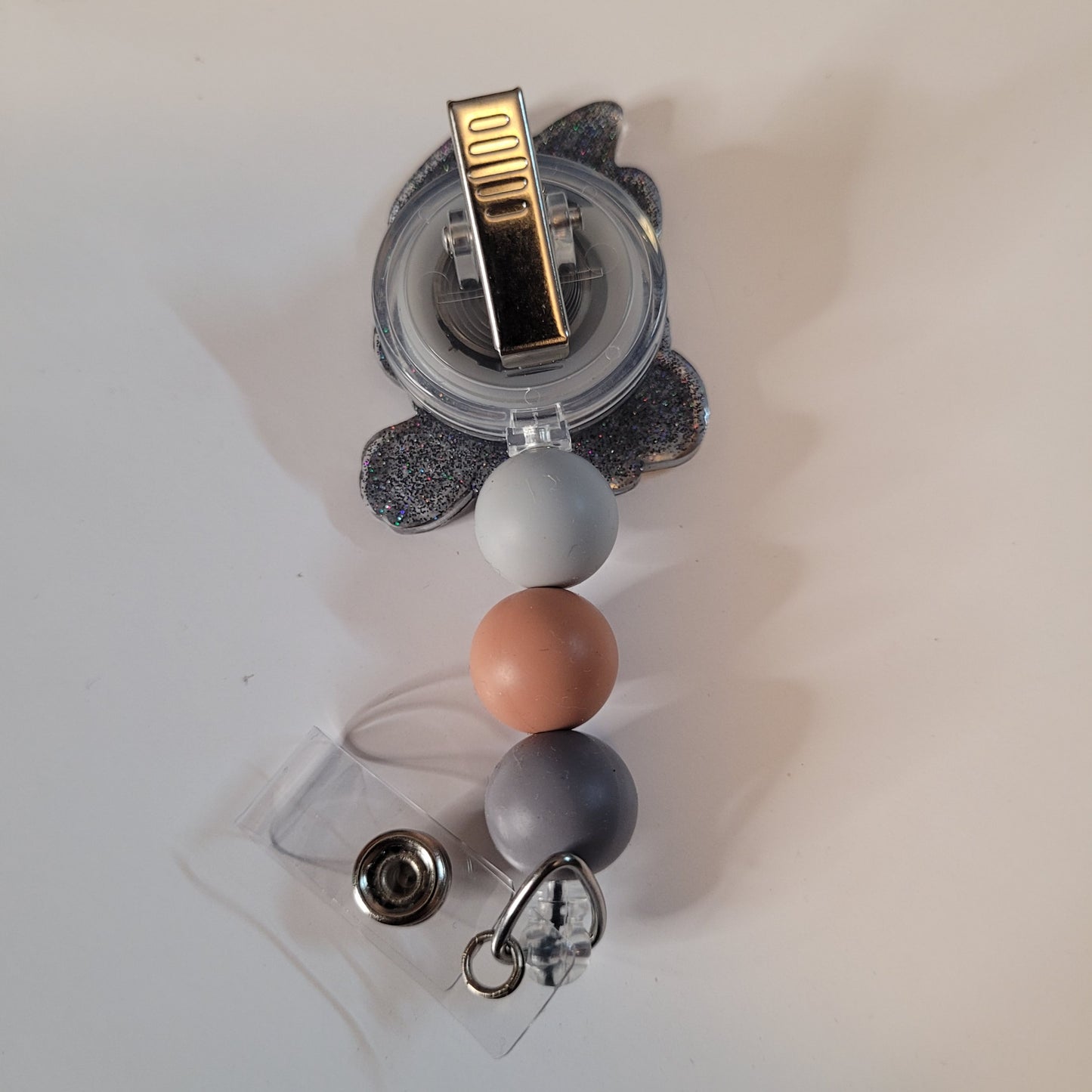 Clear holder with colorful beads and a gold clip on a light background