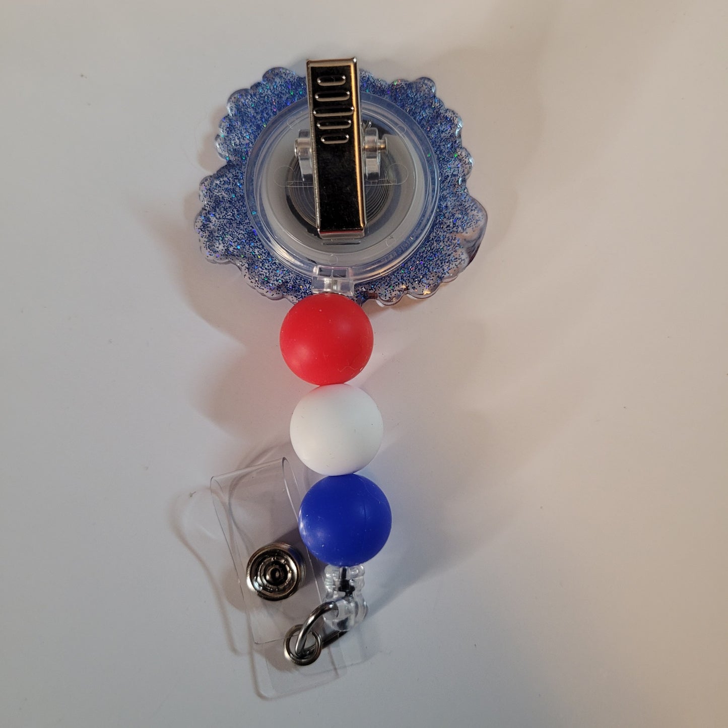 Retractable badge holder with red, white, and blue balls on a white background
