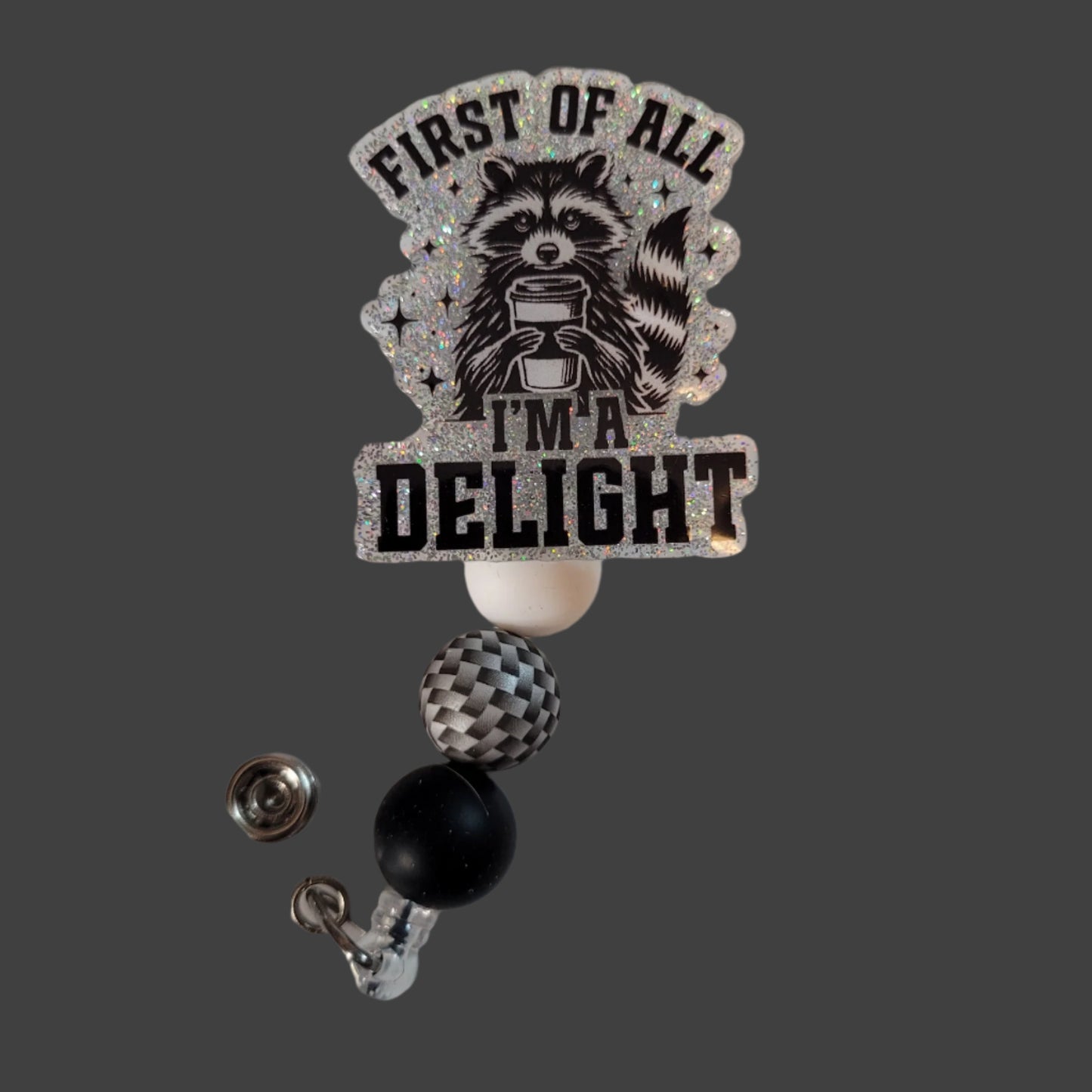 Badge holder with raccoon design and text 'First of all I'm a Delight' on a light background