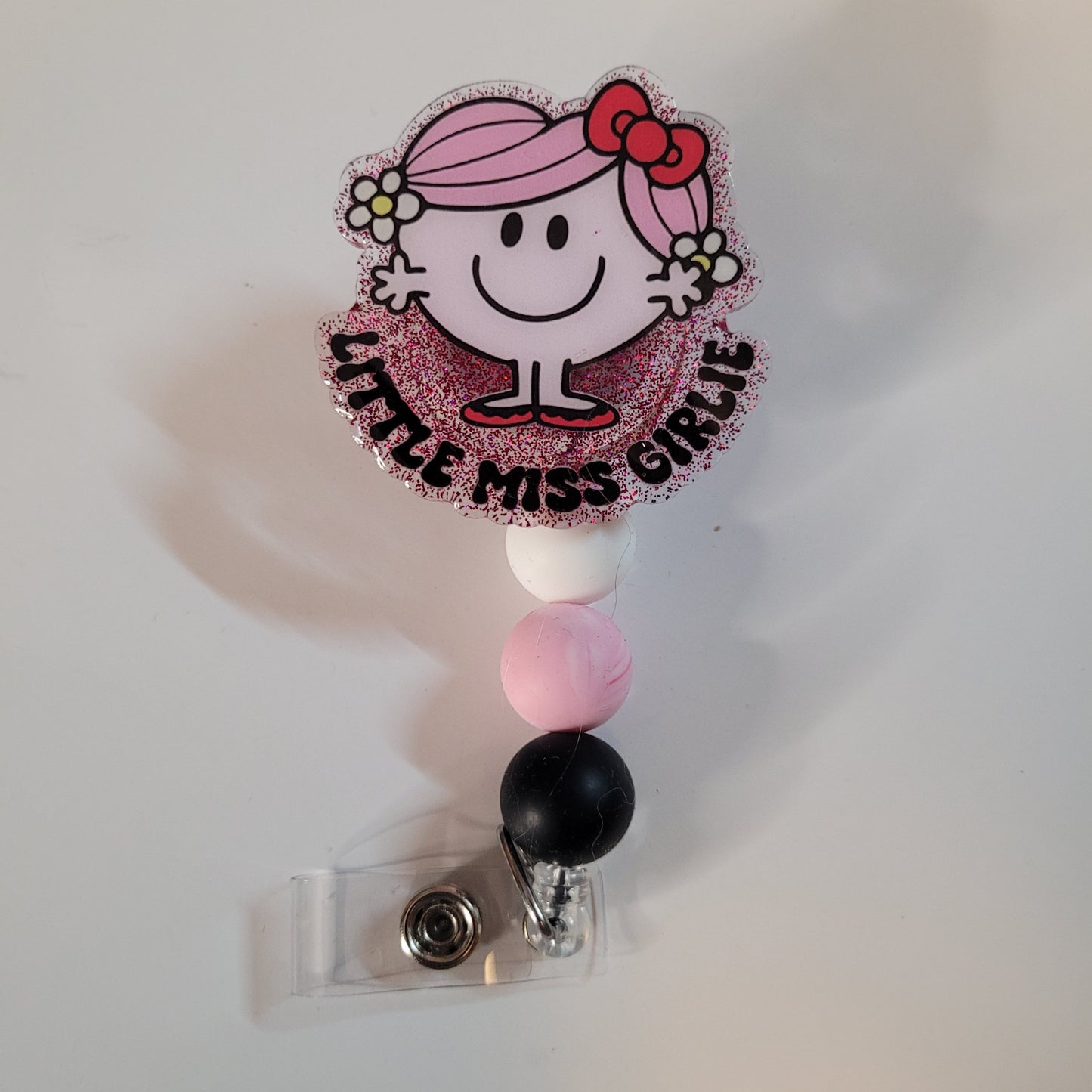 Retractable badge holder with 'Little Miss Girlie' design on a white background