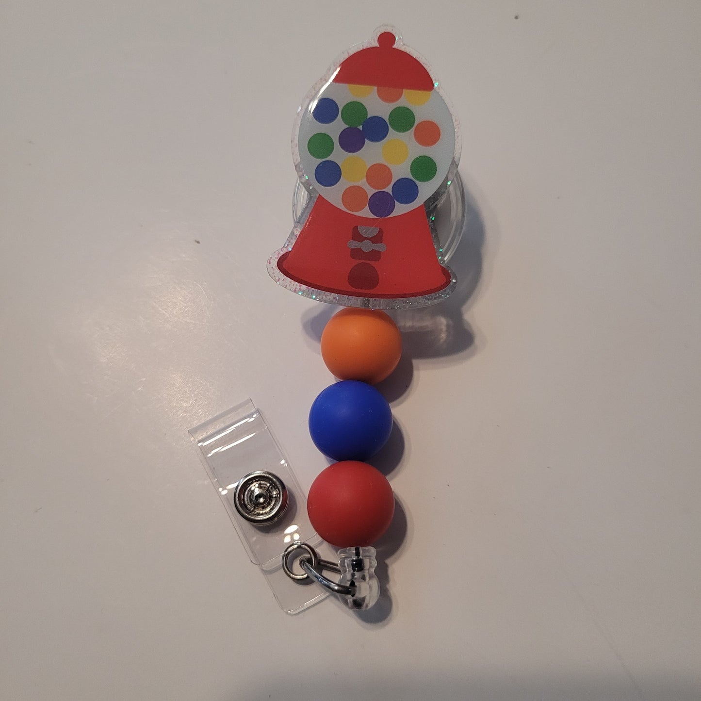 Colorful gumball machine badge holder with three beads on a white background