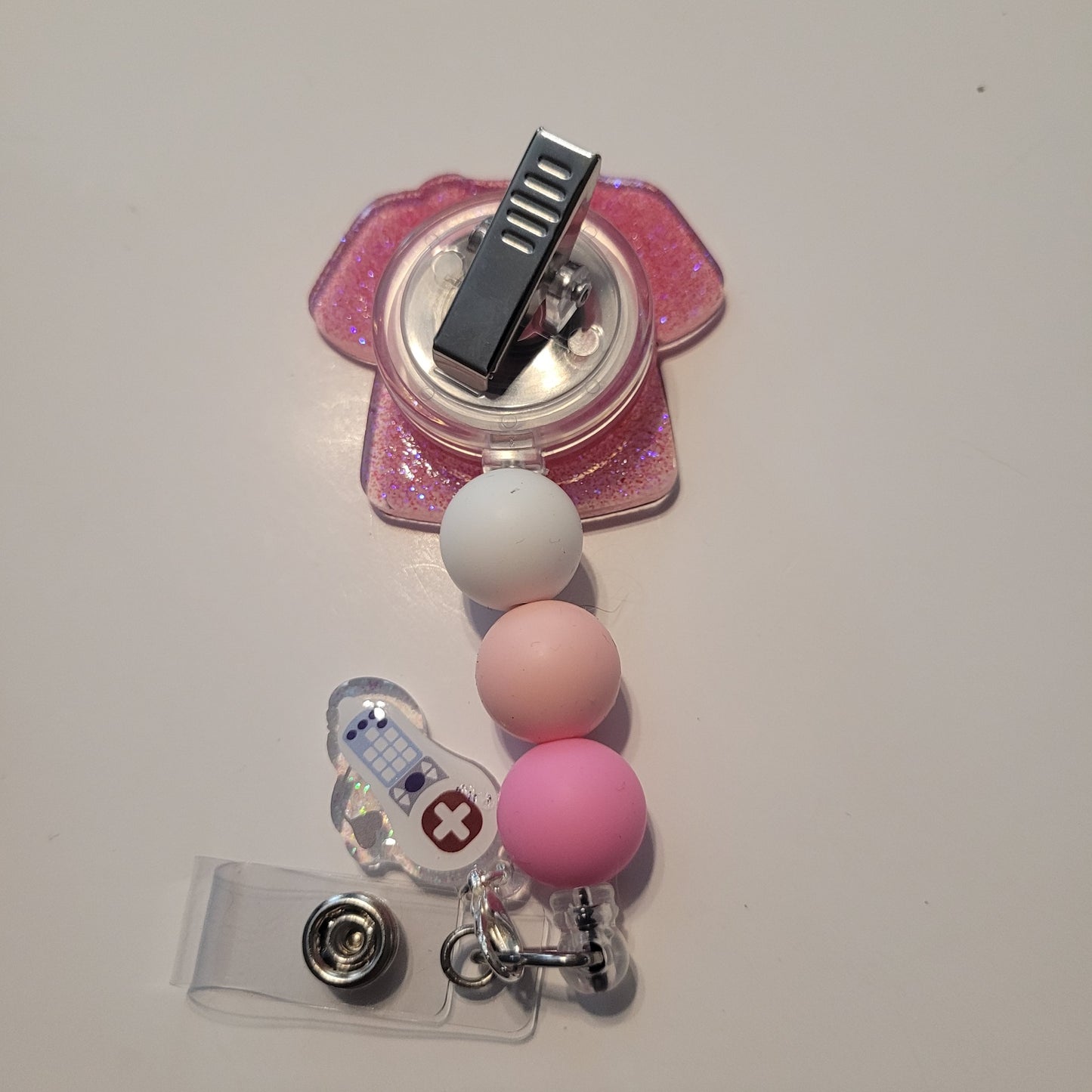Pink and white badge holder with a clip on a light gray background
