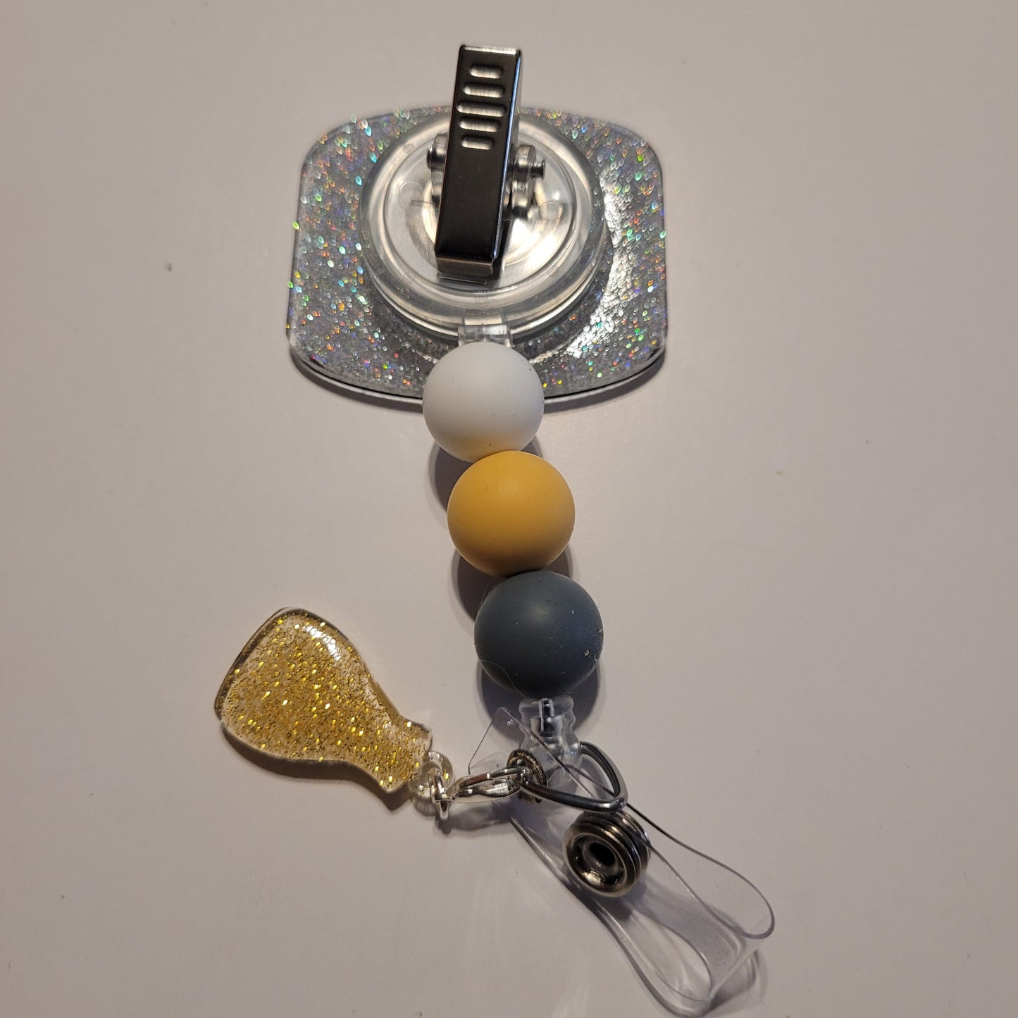 Retractable badge holder with colorful beads and glittery accents on a light gray background