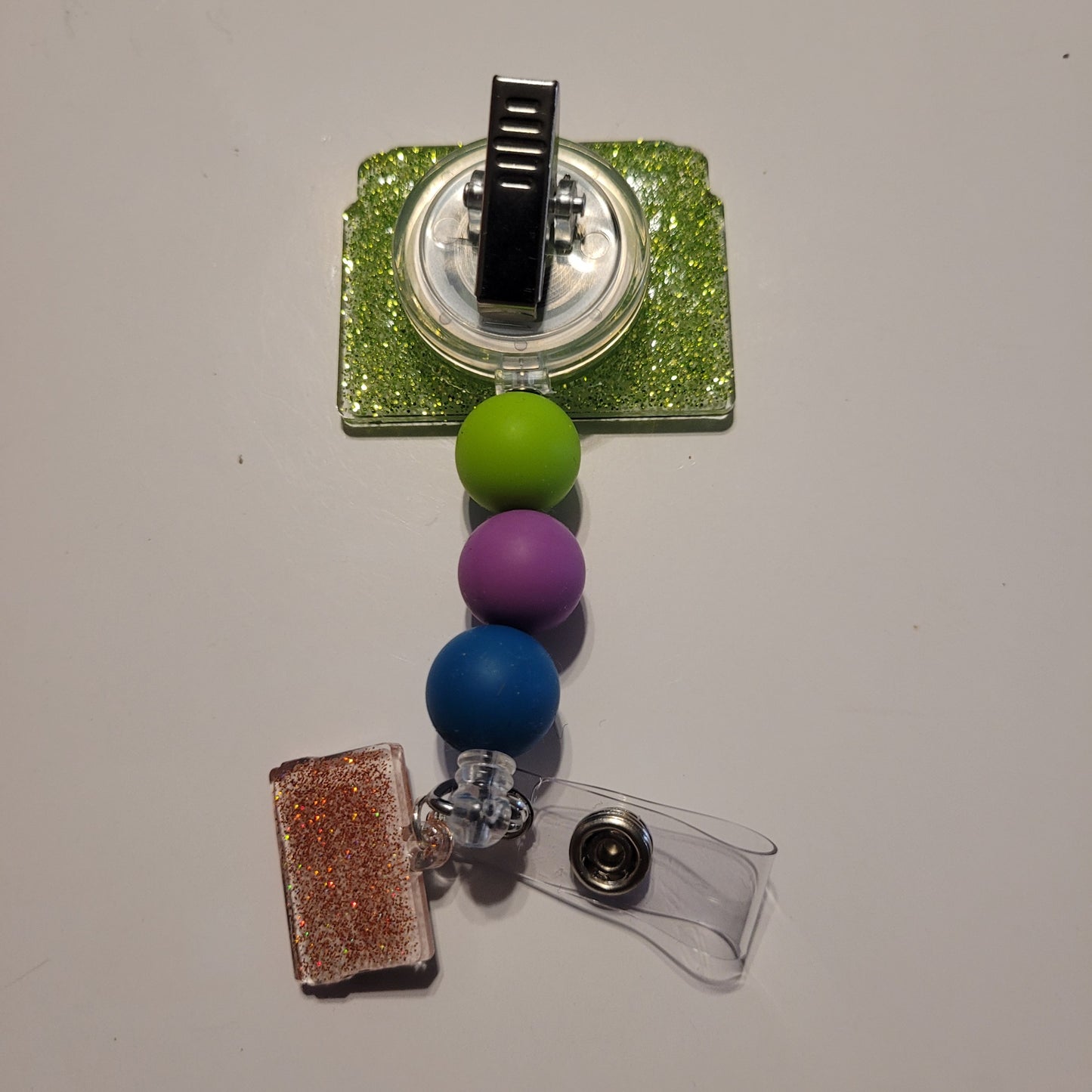 Badge holder with colorful beads and glittery accents on a plain background
