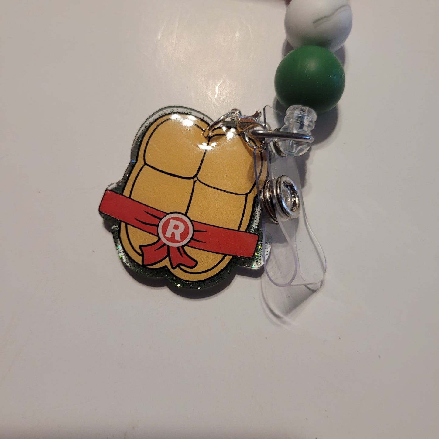 Tortoise shell badge holder with red belt and letter 'R' on a white background