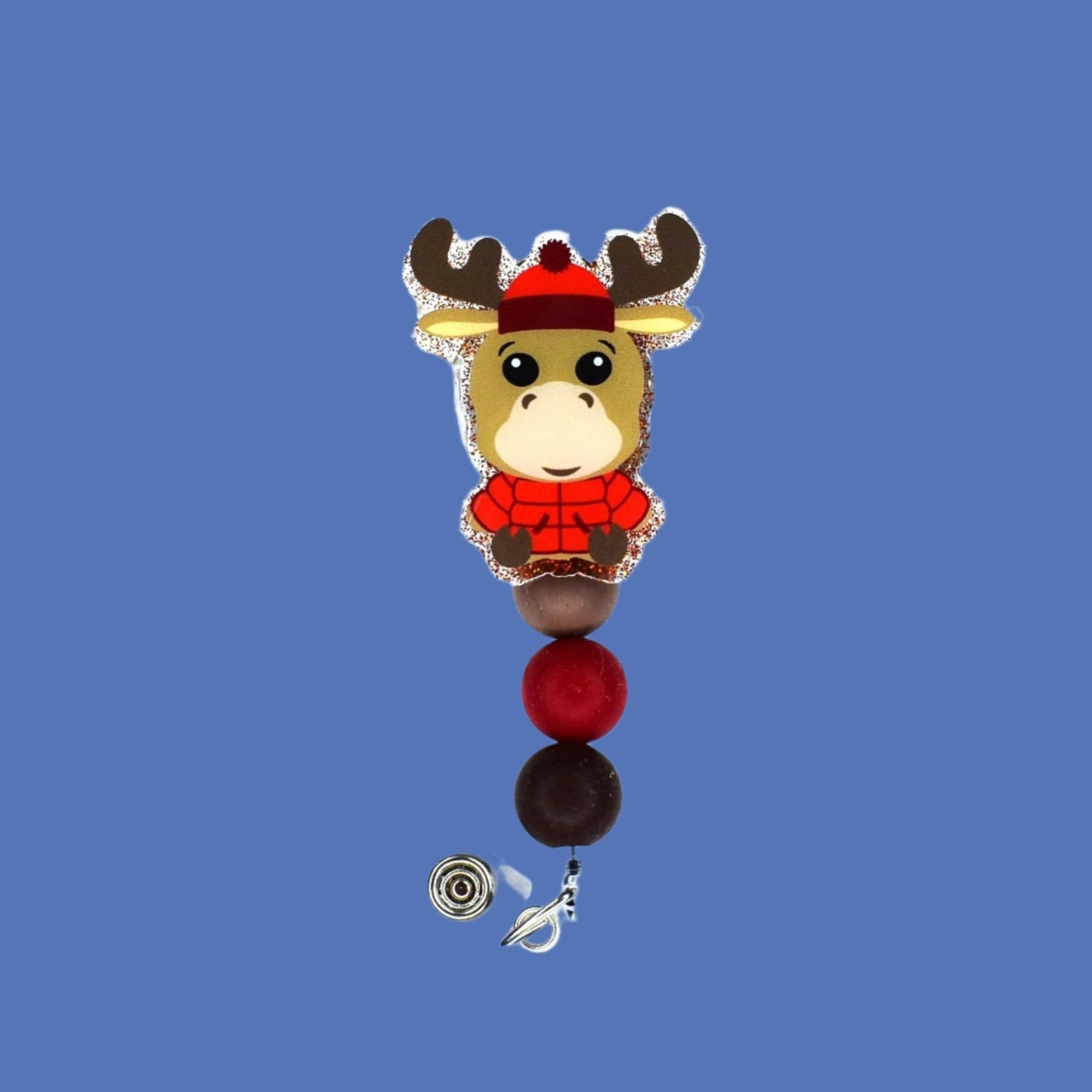 Introducing the Badge Reel Parka Moose! Showcasing a red puffy parka and a cozy knit cap, this charming moose is sure to bring a smile to your face. This stylish badge reel is finished with a red glitter base and three carefully chosen silicone beads.