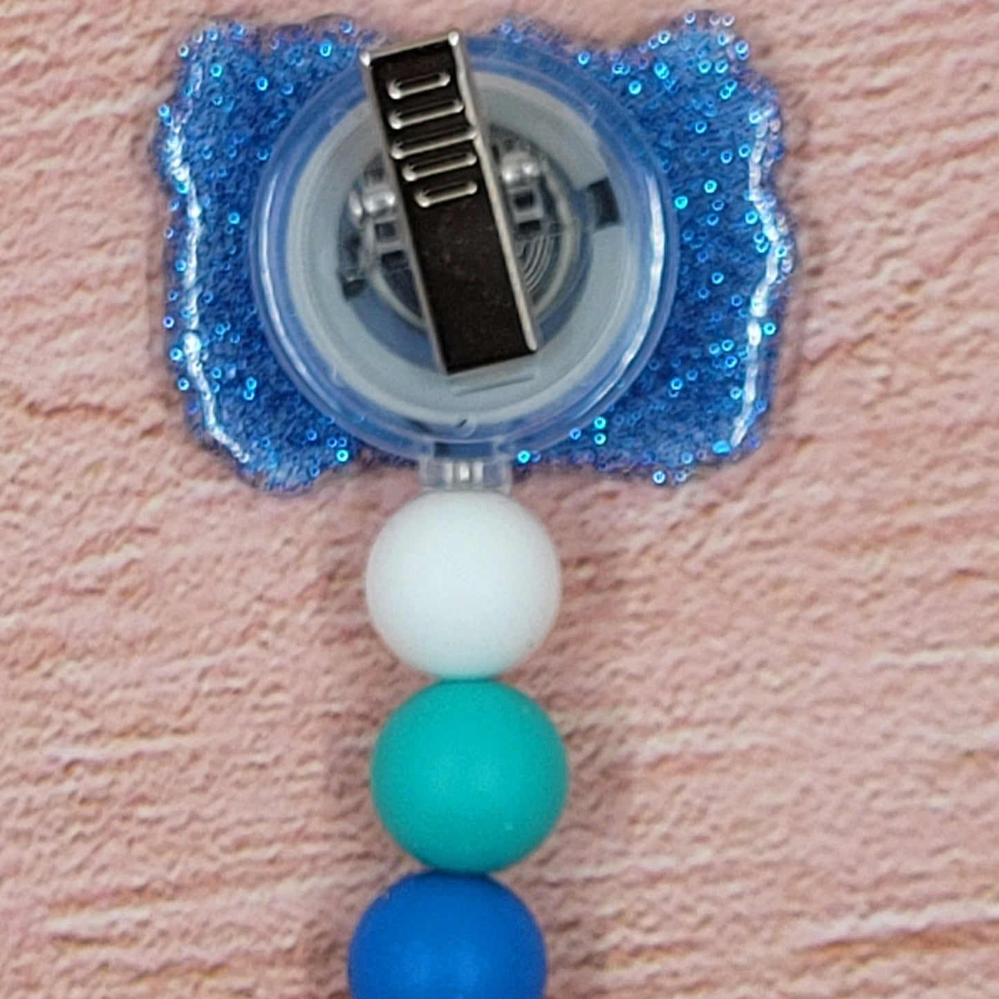The Badge Reel Alien Drink Party showcases a group of 626s indulging in their preferred beverages. The elegant design is enhanced by a sparkling blue base and three color-coordinated beads.