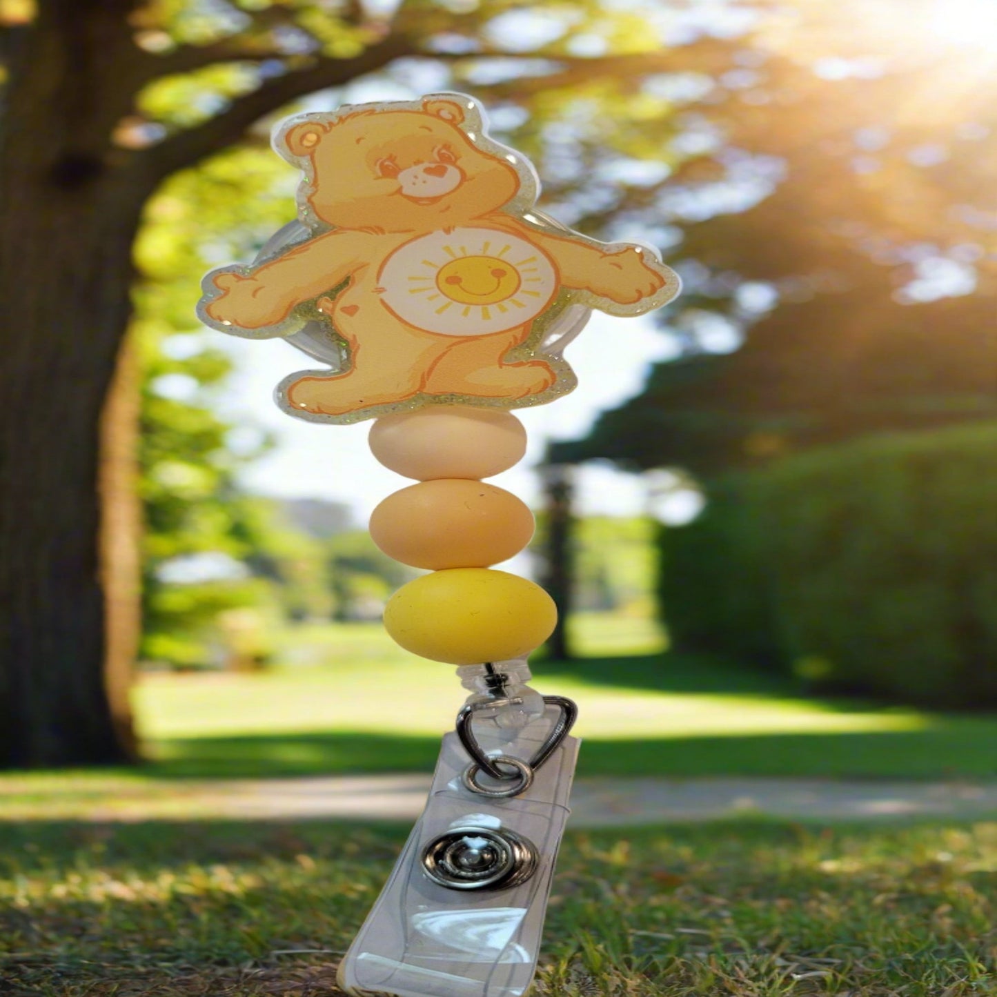 Looking for a charming badge reel? Well, look no further because we've got our Funshine Bear here! With a glittery yellow back and 3 matching silicone beads, it's perfect for all the bear lovers out there. This is 1 of 5 variations.