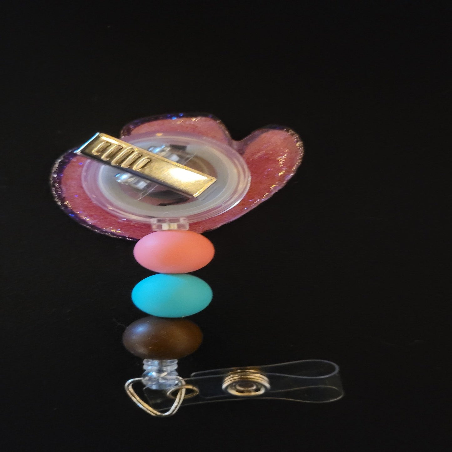 Every cowgirl needs a hat. This acrylic badge reel showcases a classic cowgirl hat decorated with flowers. A pink glitter back and 3 silicone beads finish the look.