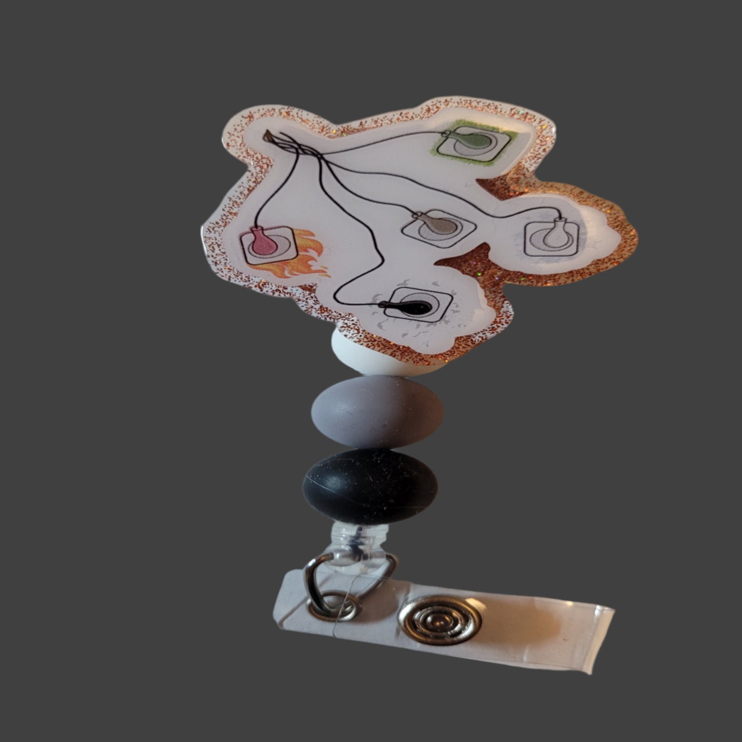 Upgrade your work ID game with our latest release of Medical Badge Reels - the EKG Leads Badge Reel! This unique piece features 5 leads on a white background with a pop of red glitter, complemented by 3 matching silicone beads for a complete look.