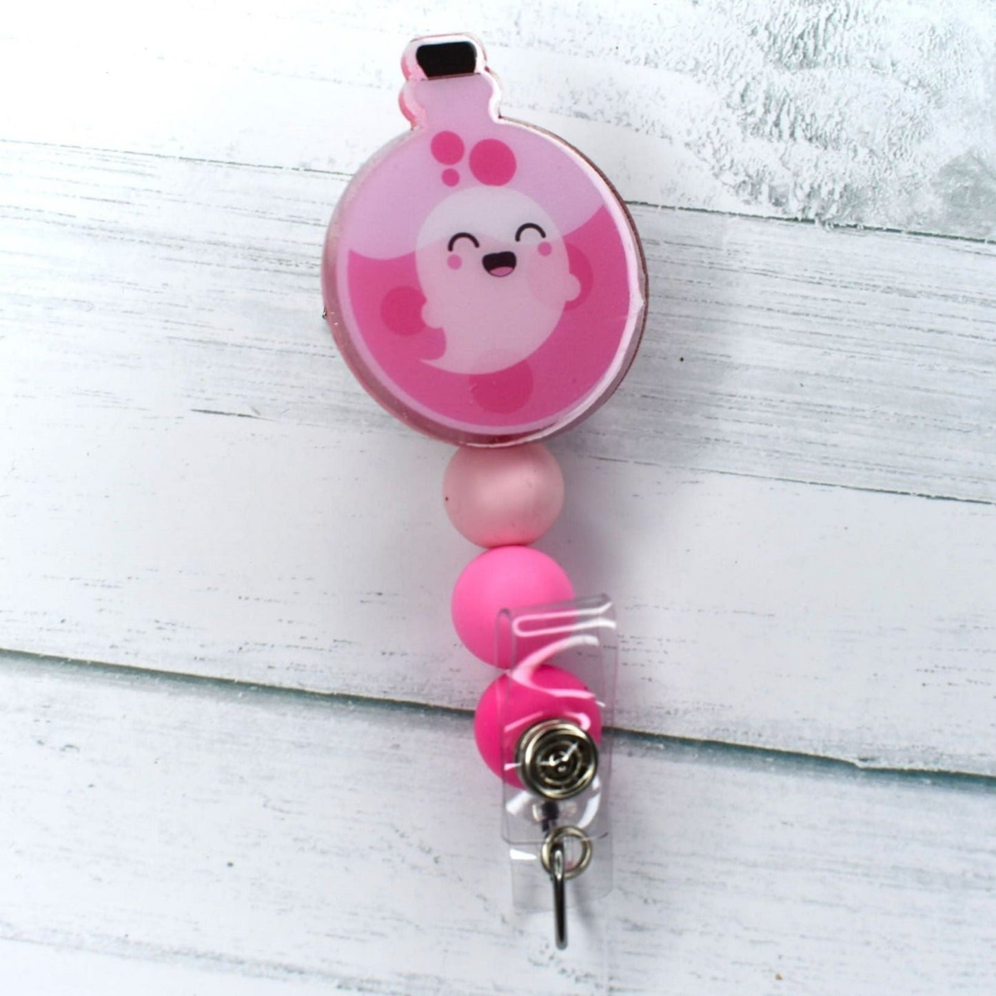 This spooky Pink Ghost Potion acrylic badge reel could be the mixture you need for a night of fright. 3 separate tones of pink silicone accent beads add to this recipe.
