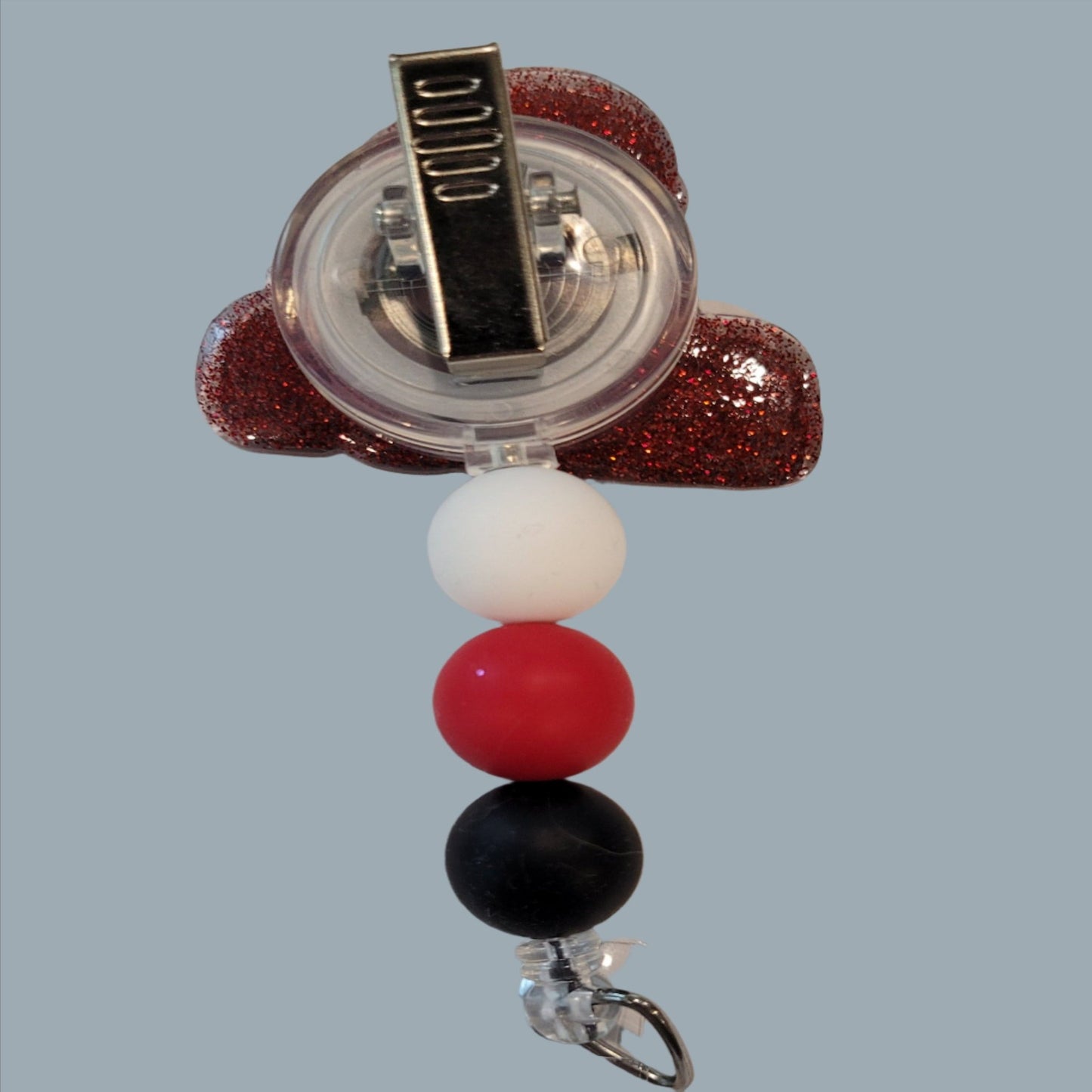 Join the fun and meet your new hero, the "Red Plumber" badge reel! This playful accessory features a red glitter back and 3 matching silicone beads for a quirky and stylish look.
