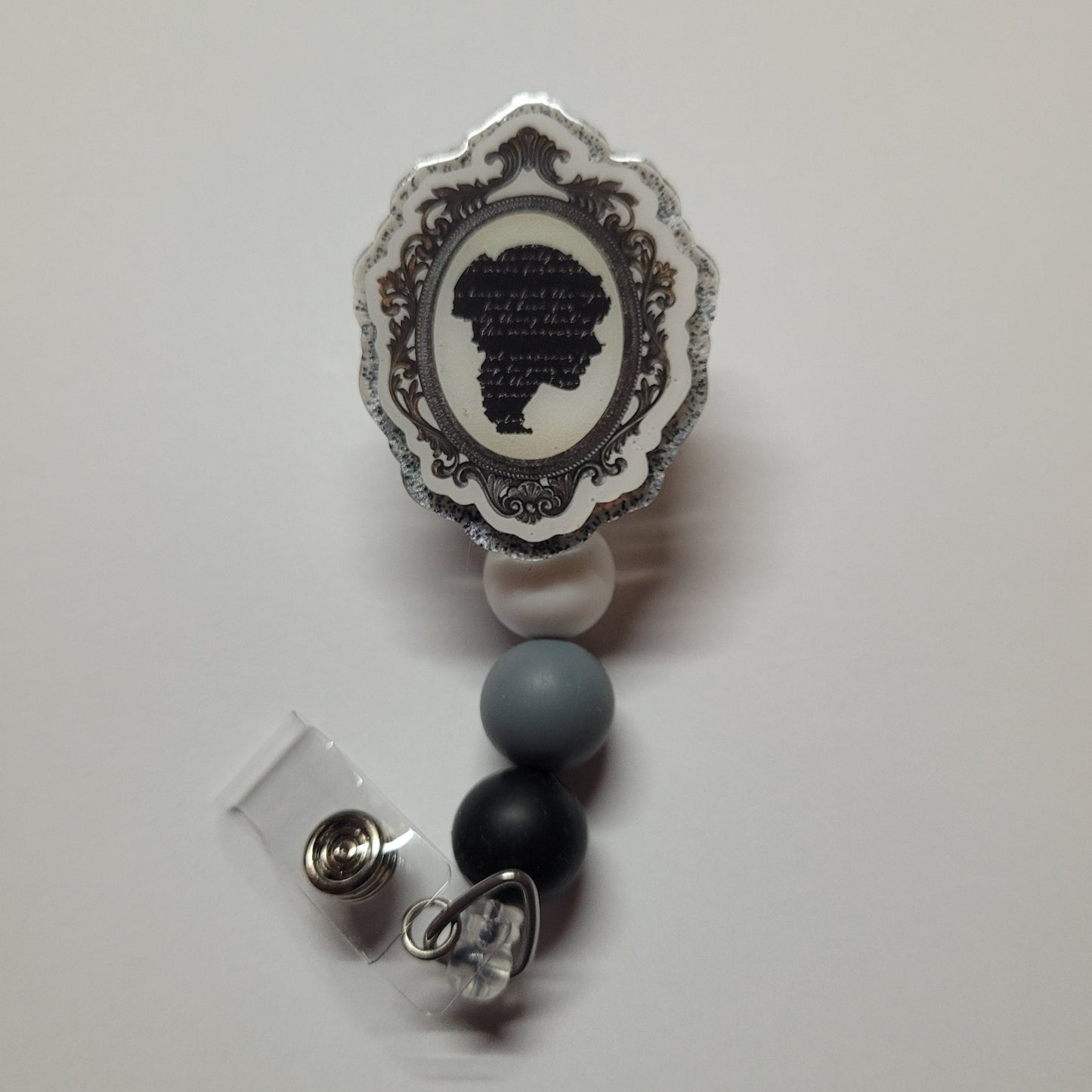 Feeling nostalgic. Here is our Silhouette badge reel depicting a late 1800s to early 1900s image of a lady with an ornate frame. Finished with 3 silicone beads.