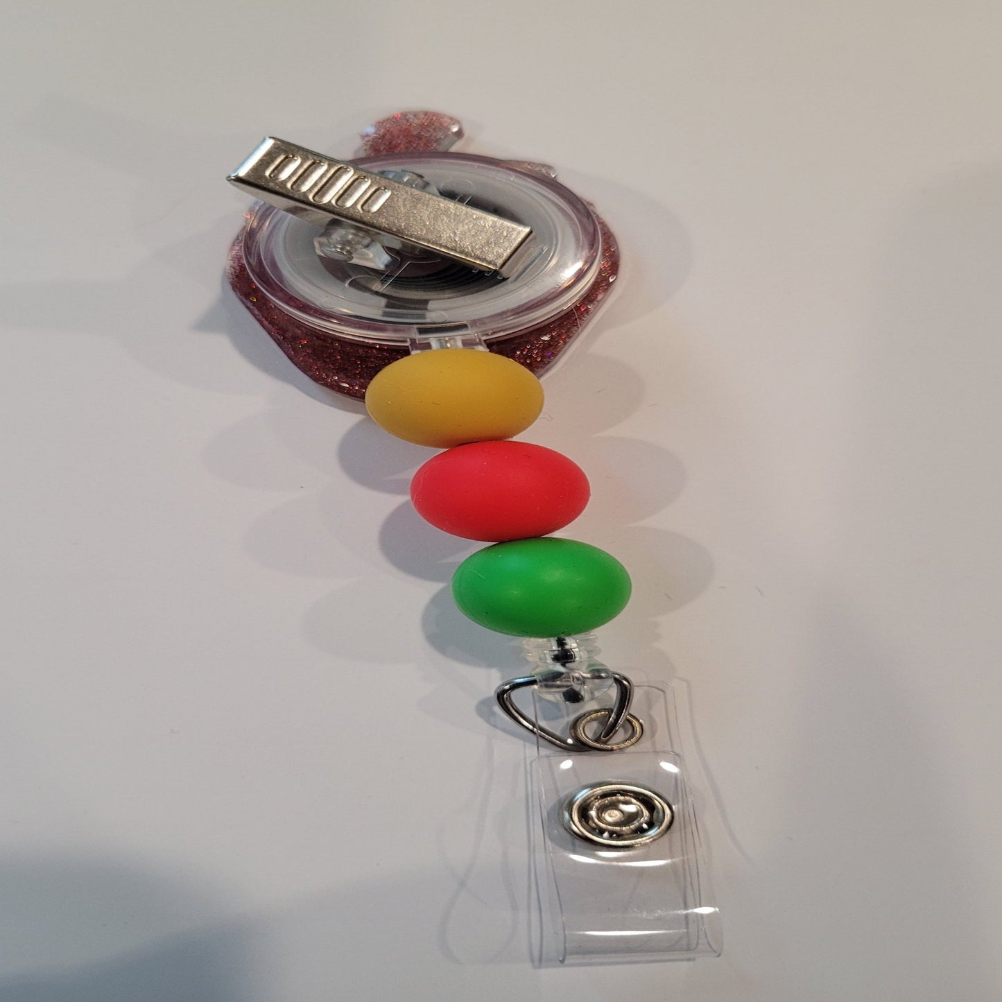 Experience the summer season with this strawberry acrylic badge reel. A red glitter back and highlighting silicone accent beads finish this tasty look.