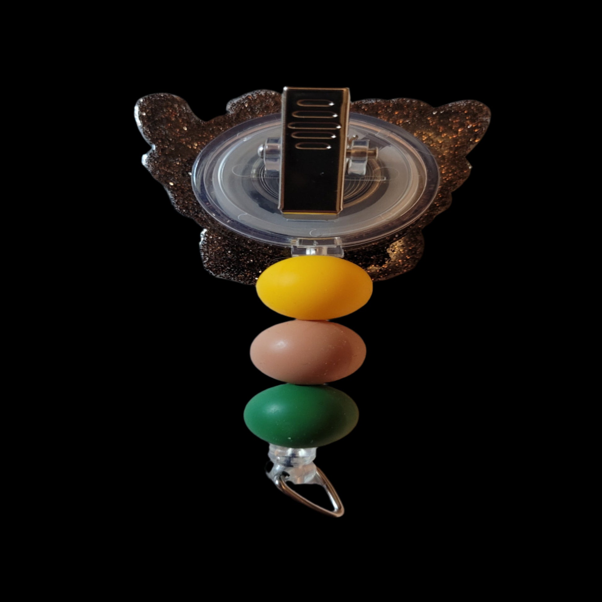 Introducing the Highland Cow Sunflower Badge Reel - adorned with a sunflower headband and playful silicone beads, all complemented by a dark brown glitter background.