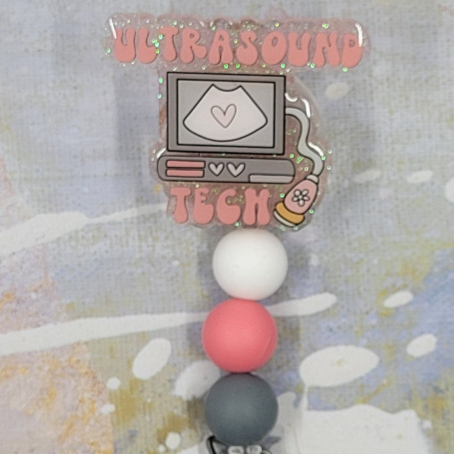 Introducing the new Ultrasound Tech Badge Reel, part of our latest collection of Medical Badge Reels available now. Featuring Ultrasound Tech in pink lettering and an ultrasound machine over a clears glitter base finished with coordinating beads, this Badge Reel is sure to catch the eye.