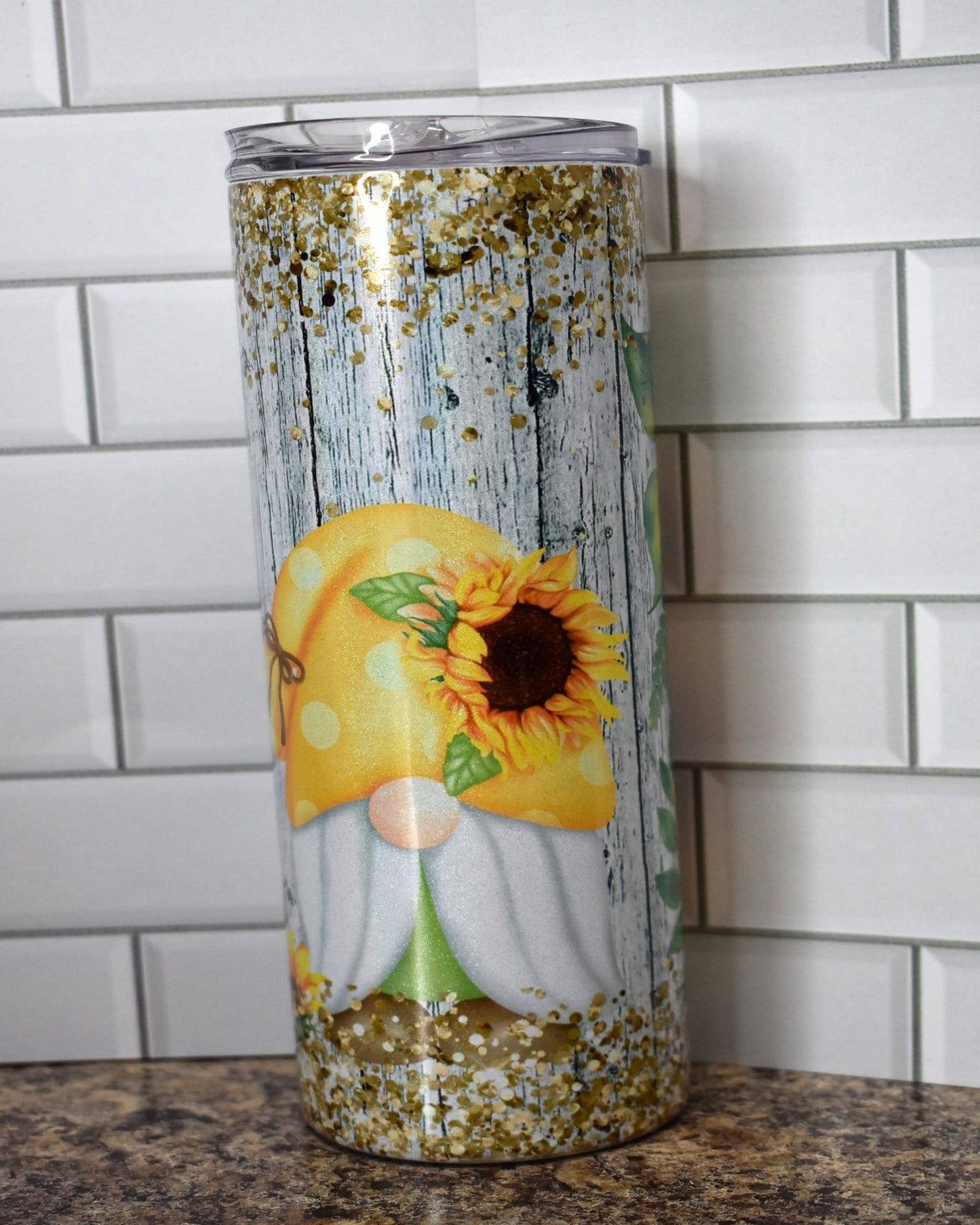 20 oz Makerflo Stainless Steel Tumbler With Gnomes Enjoying Sunflowers with chunky gold glitter flakes top & bottom. We put this image on our holographic glitter series