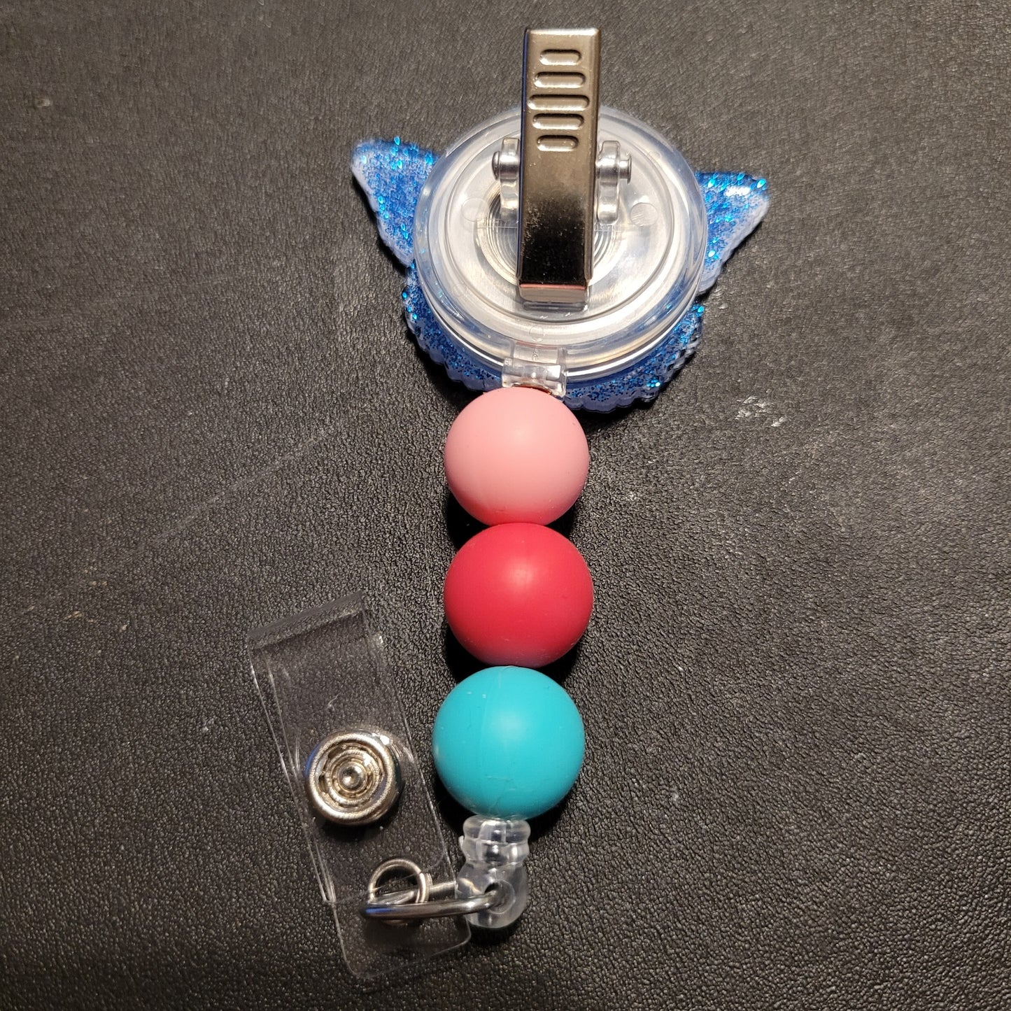 Retractable badge holder with colorful beads on a black background