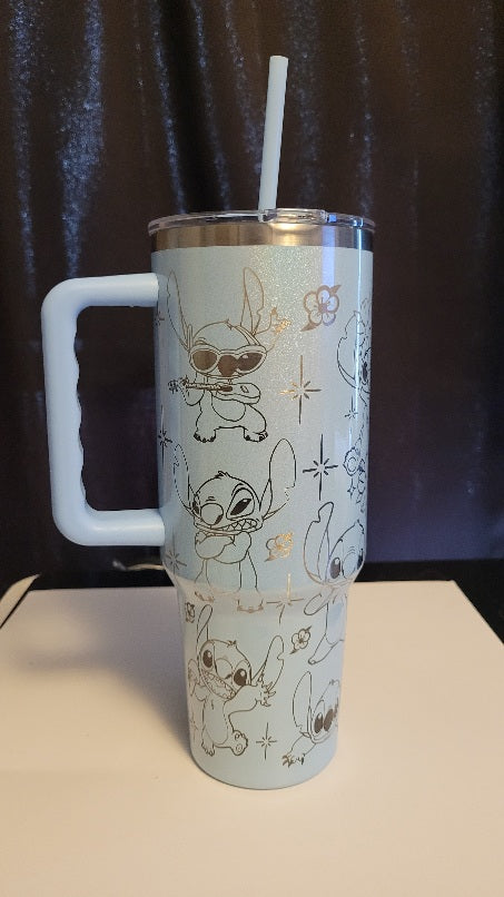 Tumbler with cartoon character designs on a light blue surface with a dark curtain background