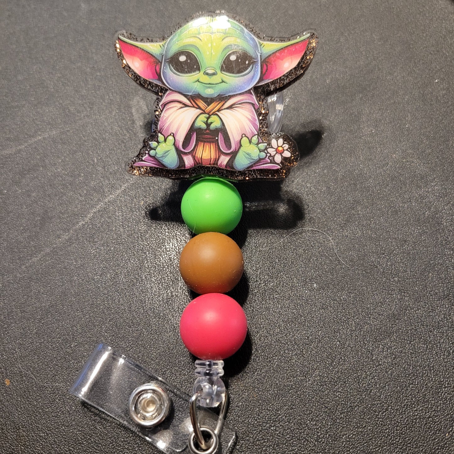 Colorful badge holder with a character design on a dark surface