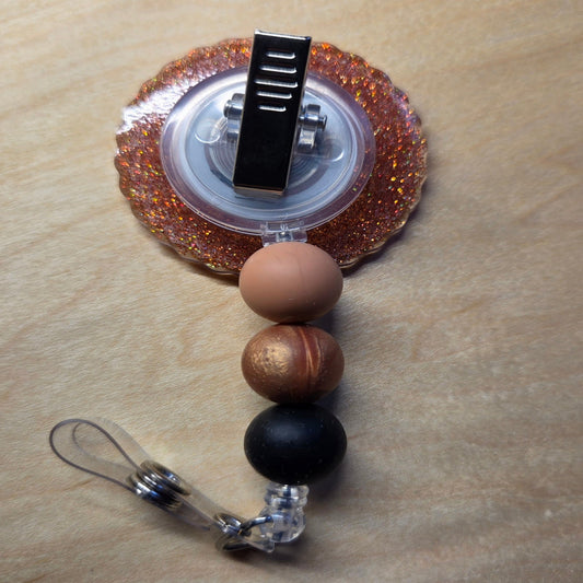 Retractable badge holder with decorative beads on a wooden surface