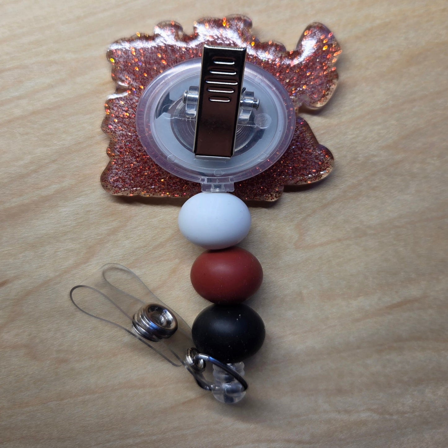 Badge holder with colorful beads and a clip on a wooden surface