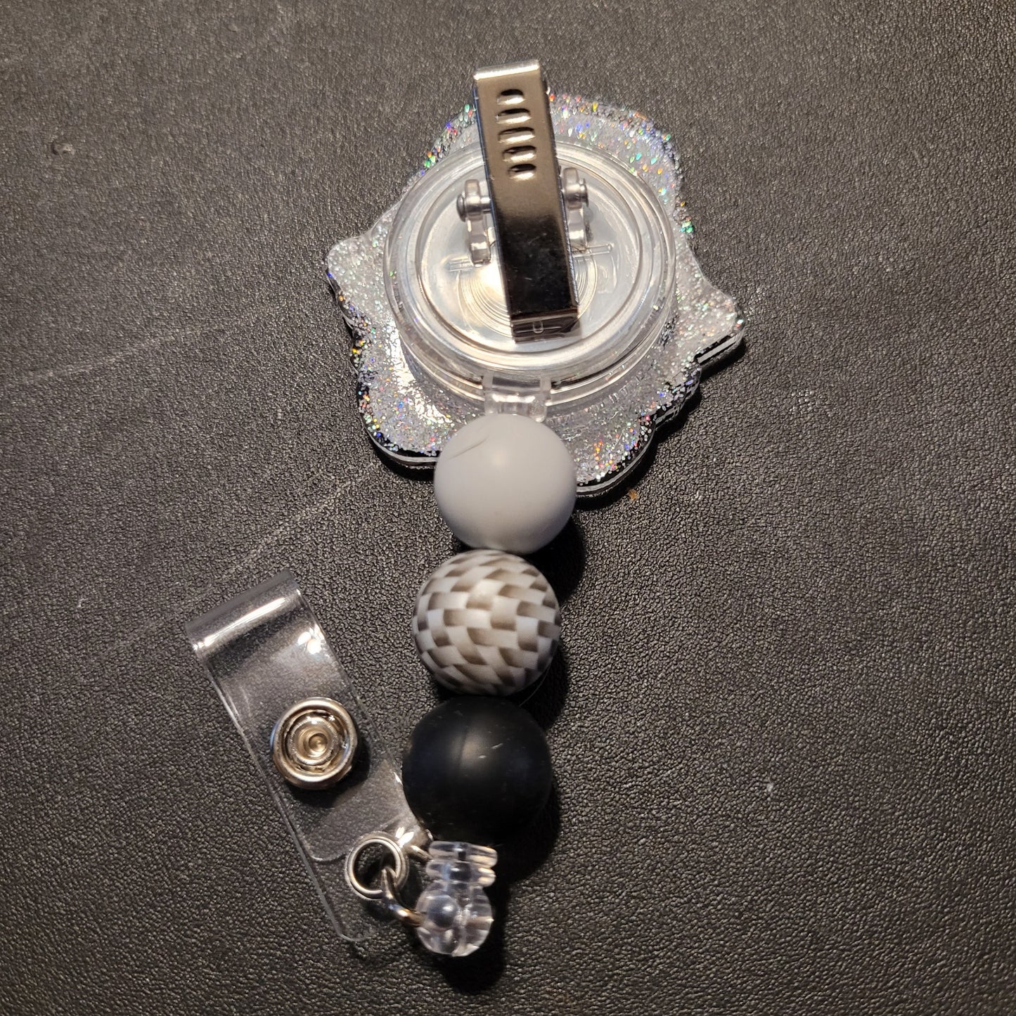 Retractable badge holder with beads on a dark surface