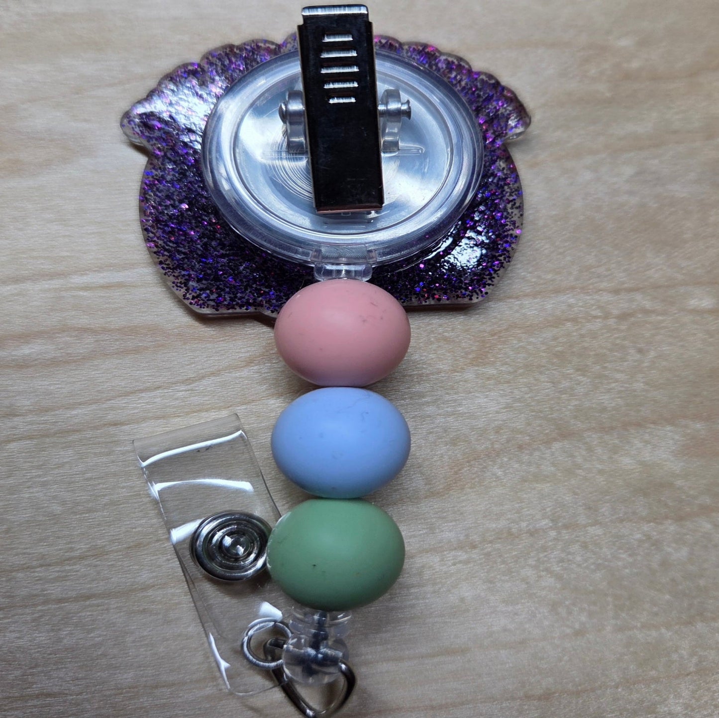 Retractable badge holder with colorful beads on a wooden surface