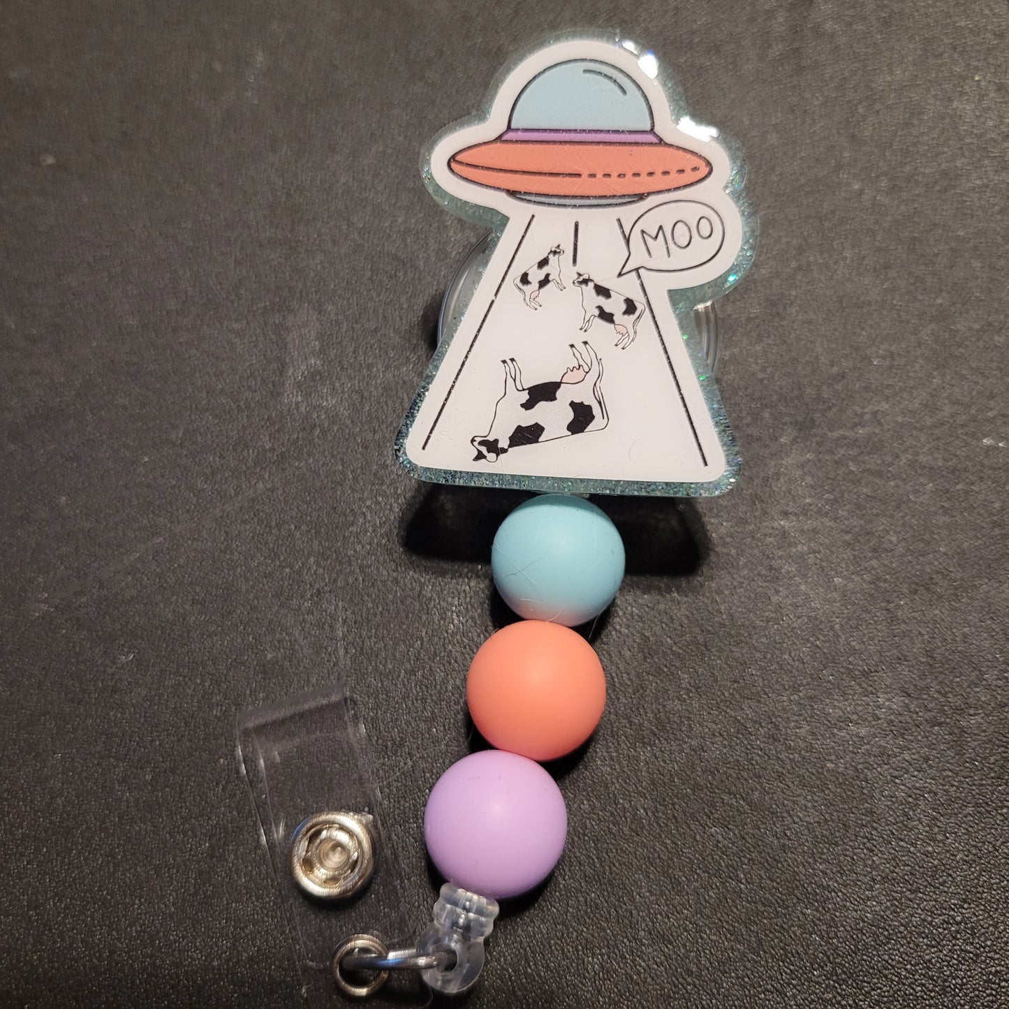 Retractable badge holder with colorful beads and alien design on a dark background