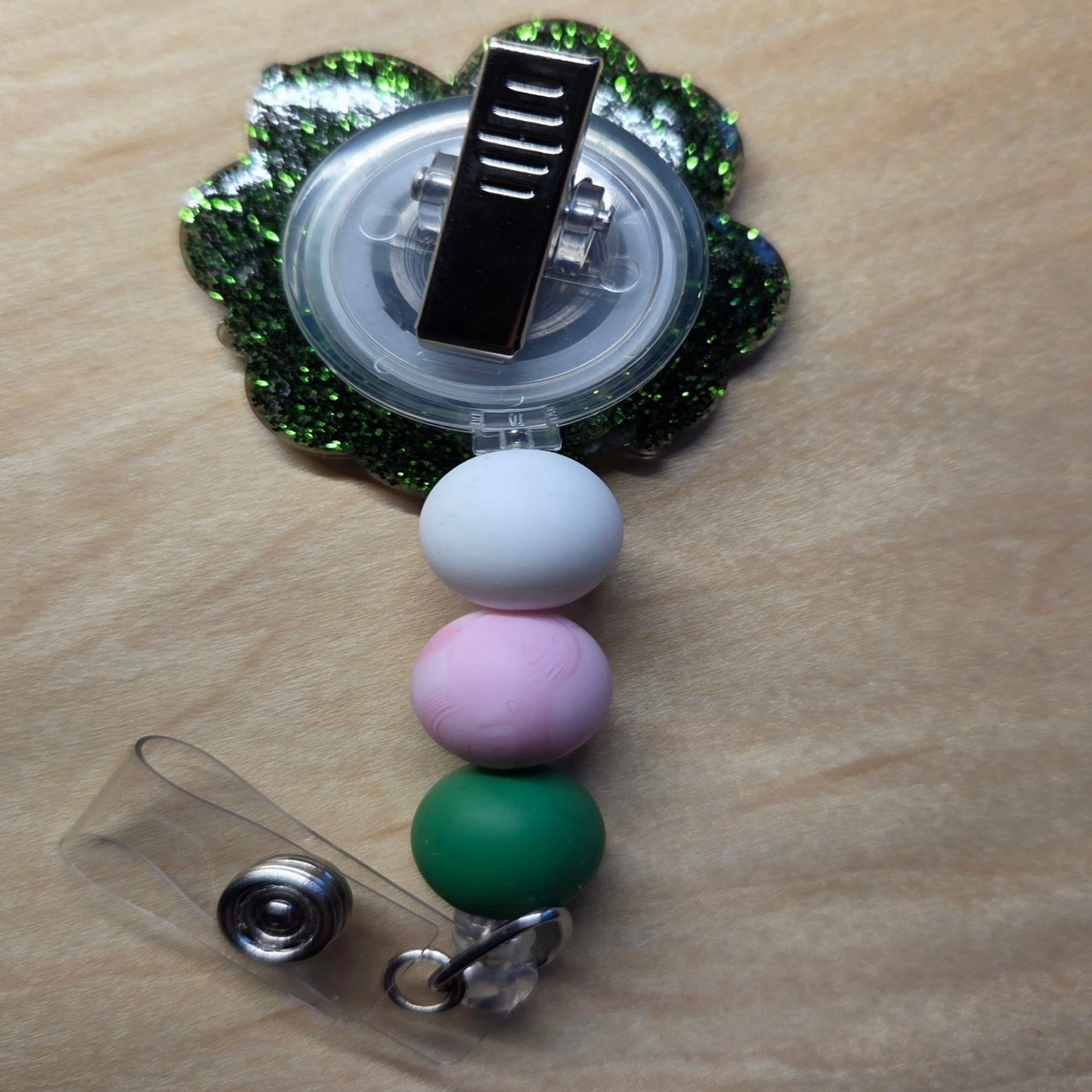 Colorful beaded badge holder with a clip on a wooden surface