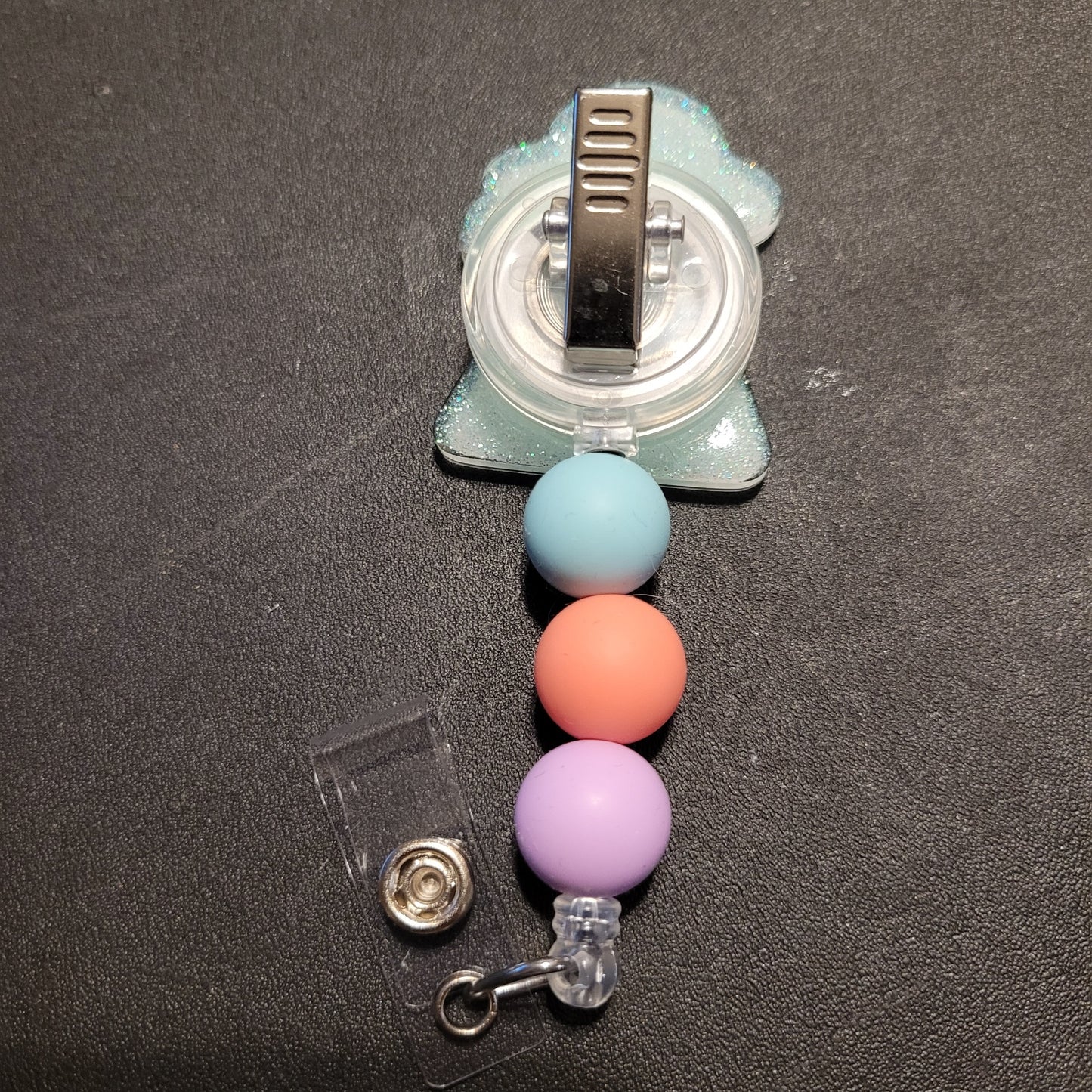 Retractable badge holder with colorful beads on a dark surface