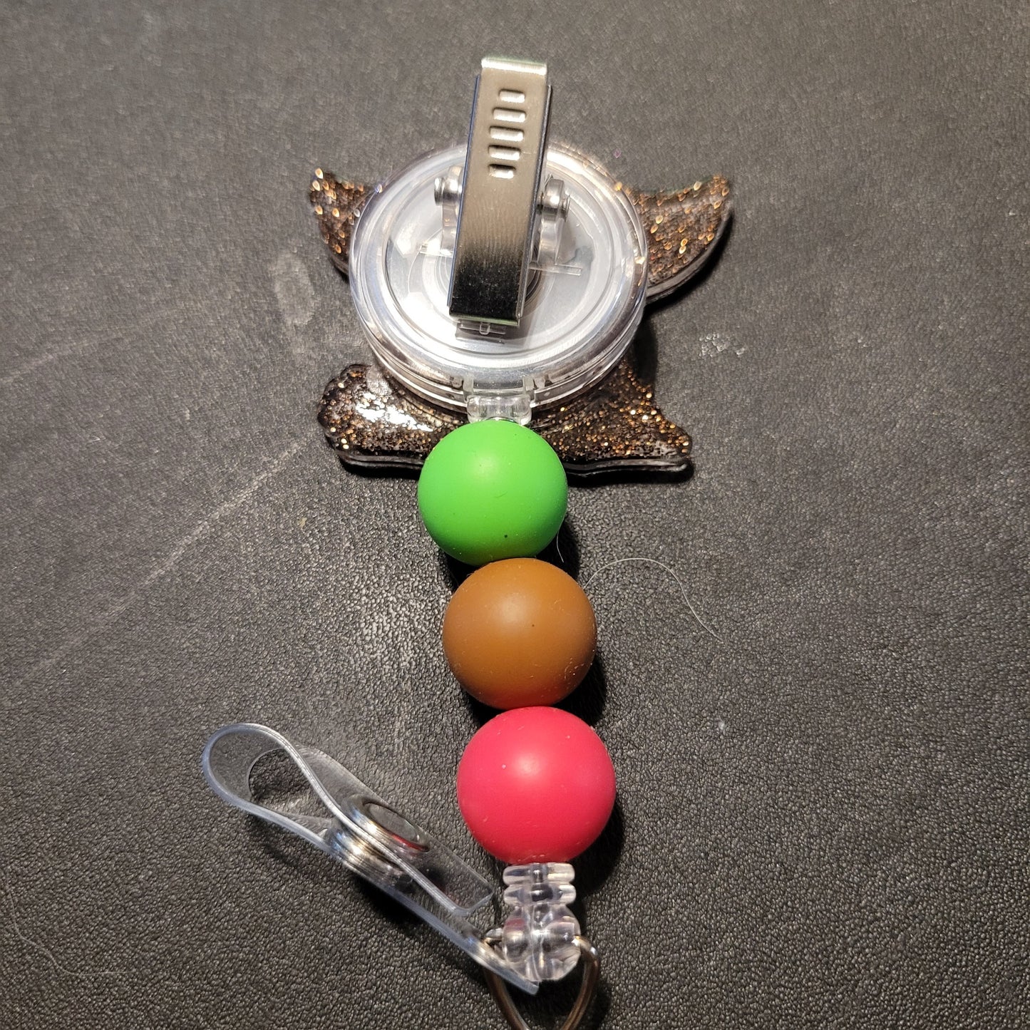 Turtle-shaped badge holder with colorful beads on a dark surface