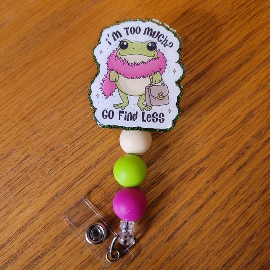 Another new one to our Animal Series... Too Much Frog. This gal frog is wearing a pink feather boa, holding her purse and ready to go. The words I'm Too Much? Go Find Less finish the front. A dazzling green glitter backing and 3 color-coordinated silicone beads add the perfect finishing touch to this out-of-this-world badge reel.