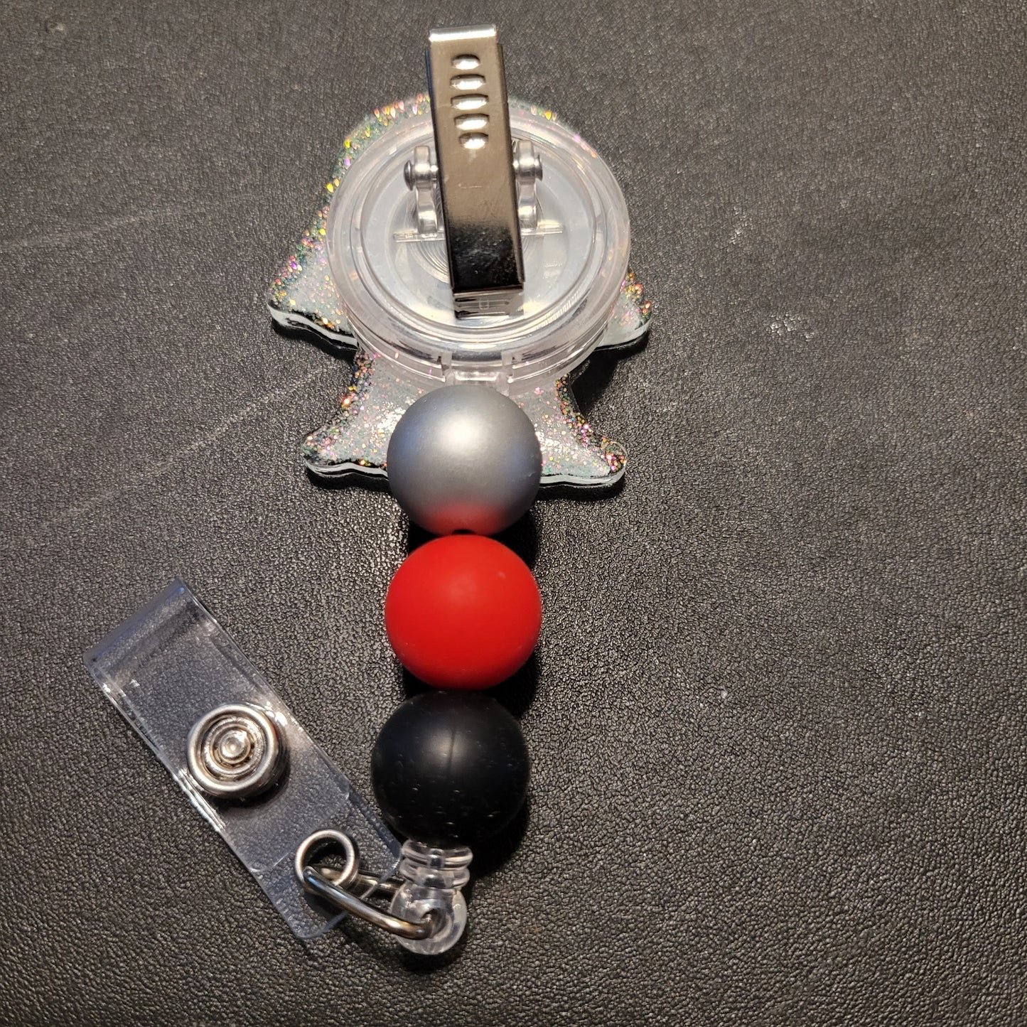 Retractable badge holder with colorful beads on a dark surface
