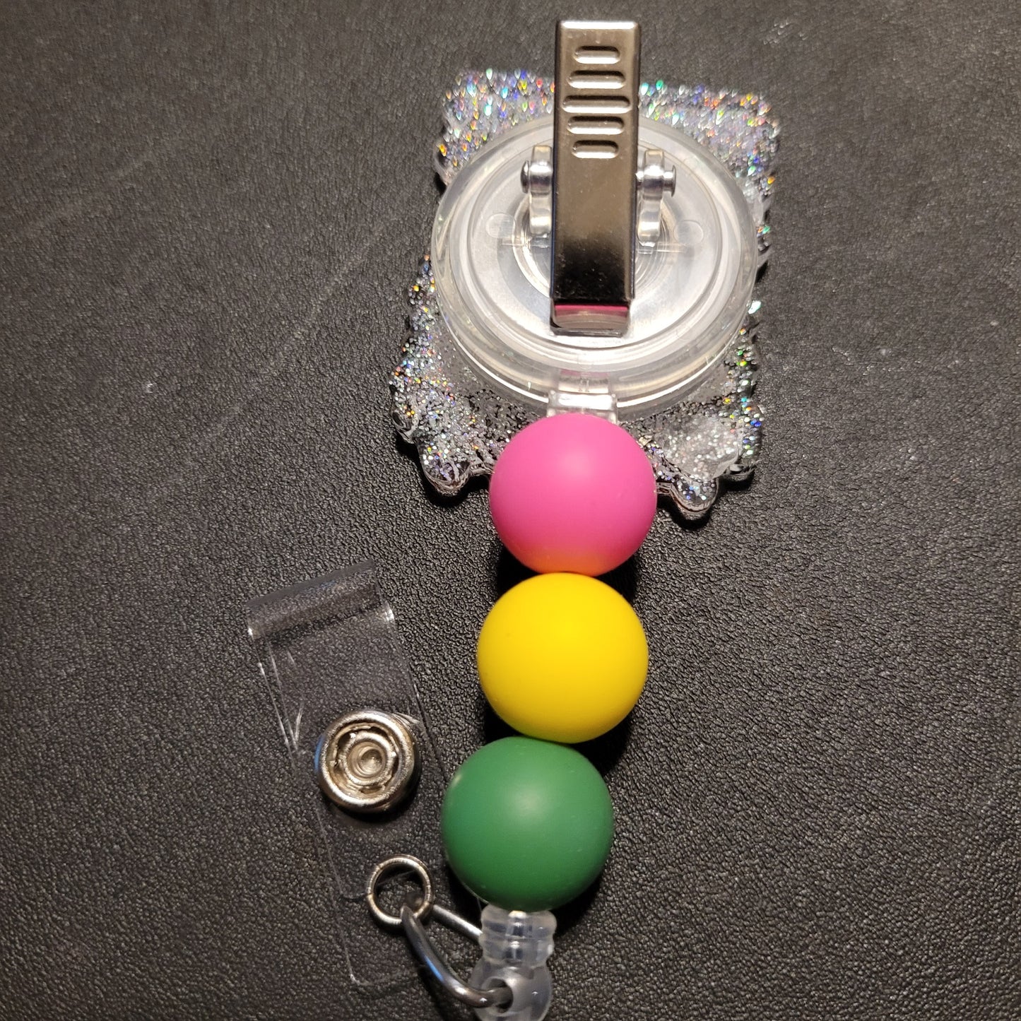 Retractable badge holder with colorful beads on a dark surface