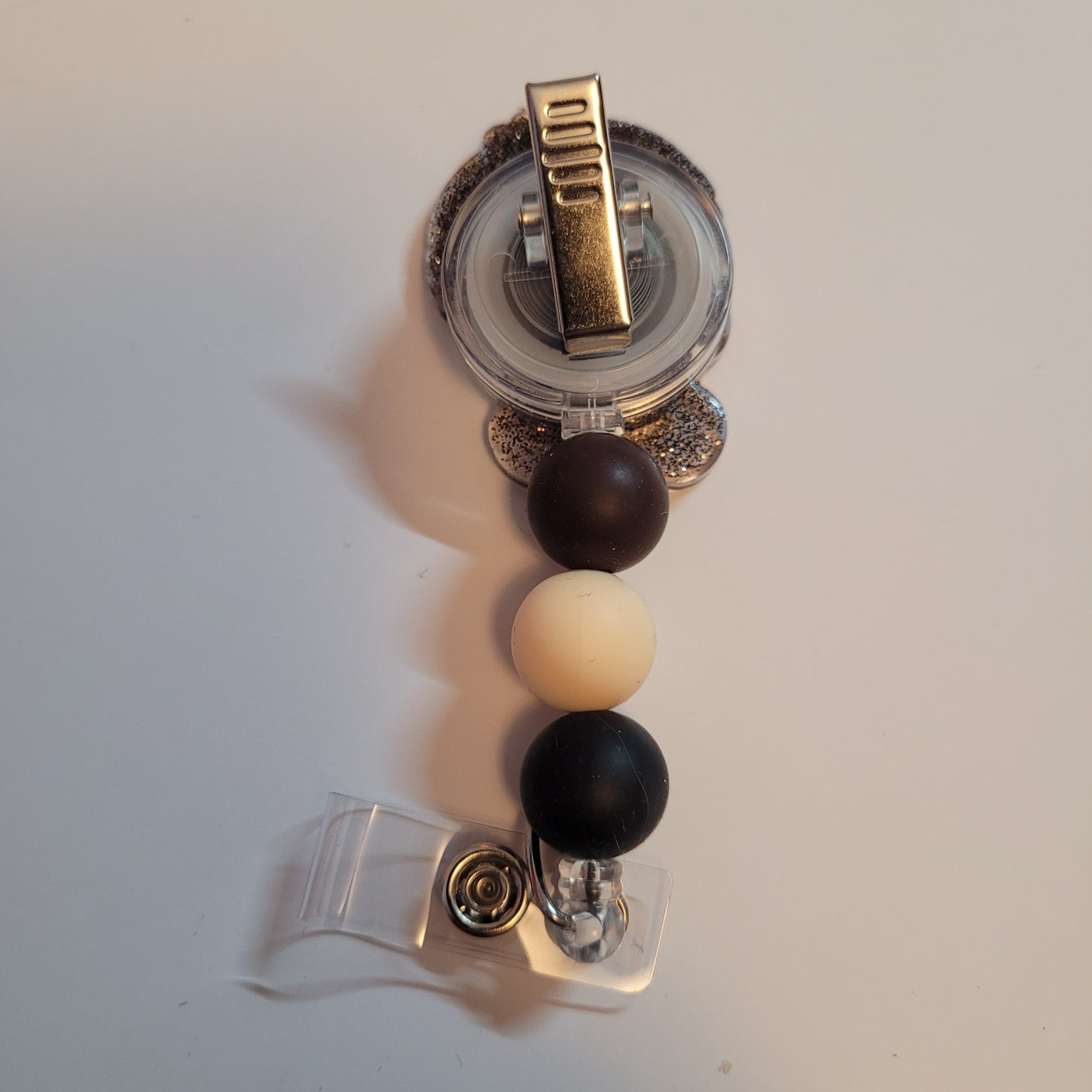 Retractable badge holder with black, white, and gold design on a white background