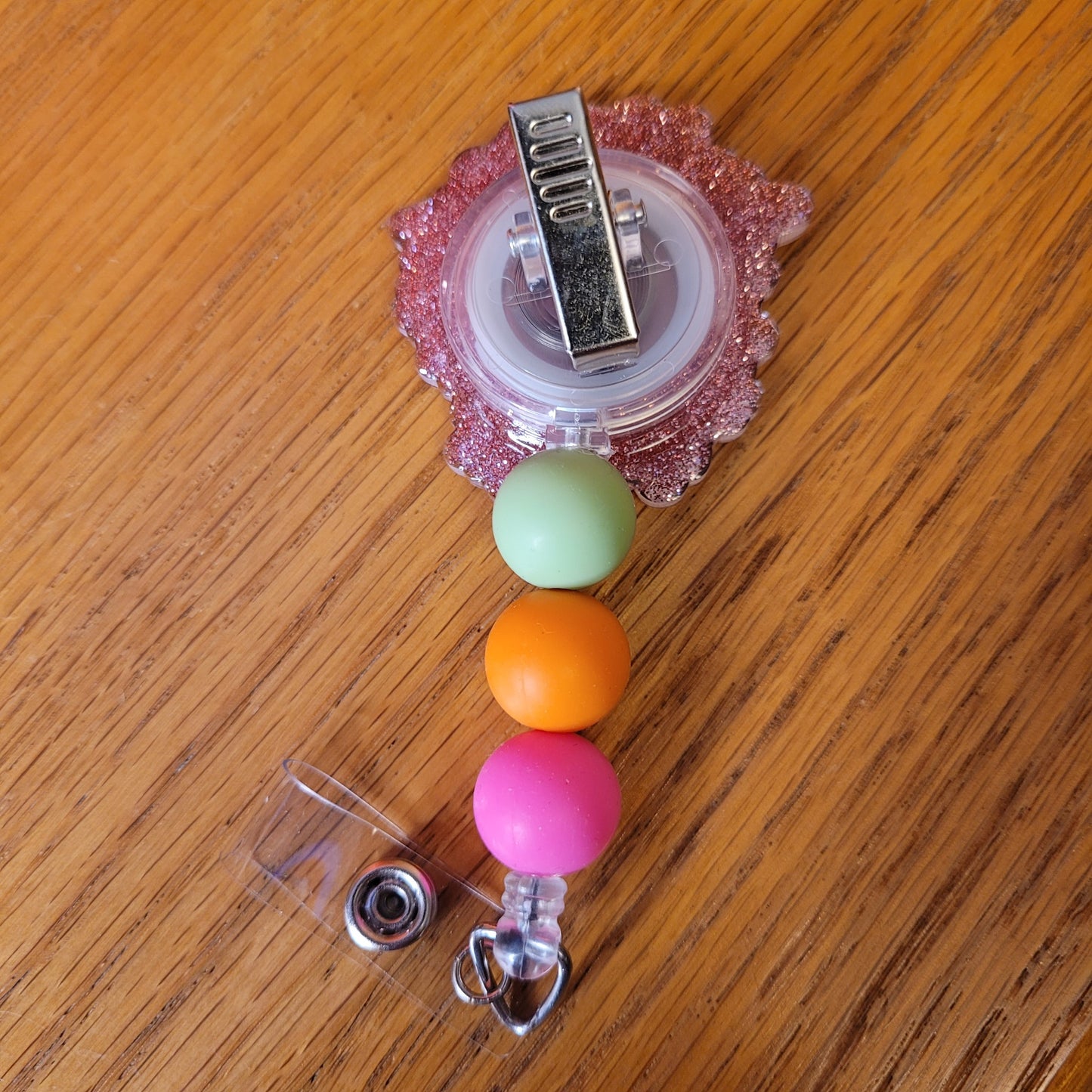 Our Flower Blast badge reel is here. Simple group of various flowers surrounded be green leaves. A sparkling rose gold glitter back and embellished with 3 silicone beads on the cord.