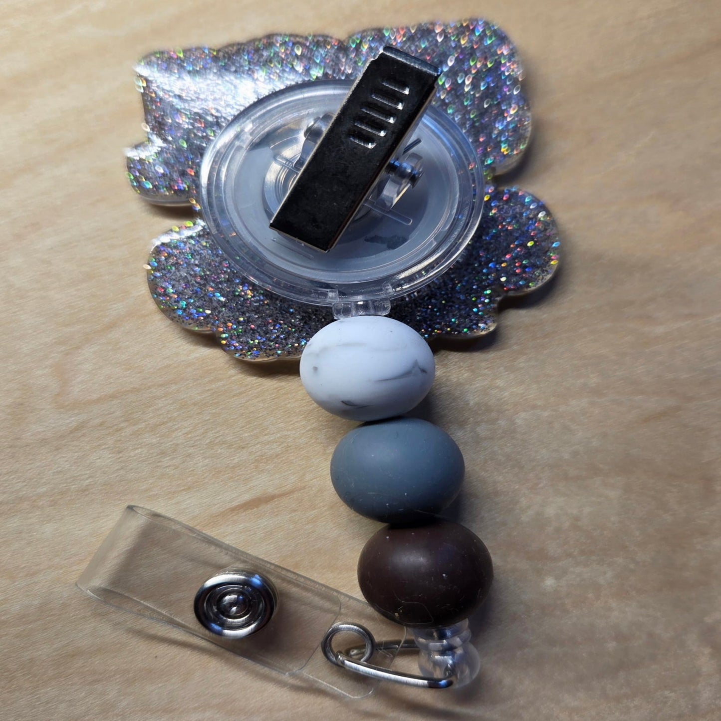 Decorative badge holder with beads and a glittery flower on a beige background