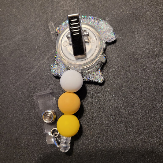 Badge holder with yellow beads and a clip on a dark background