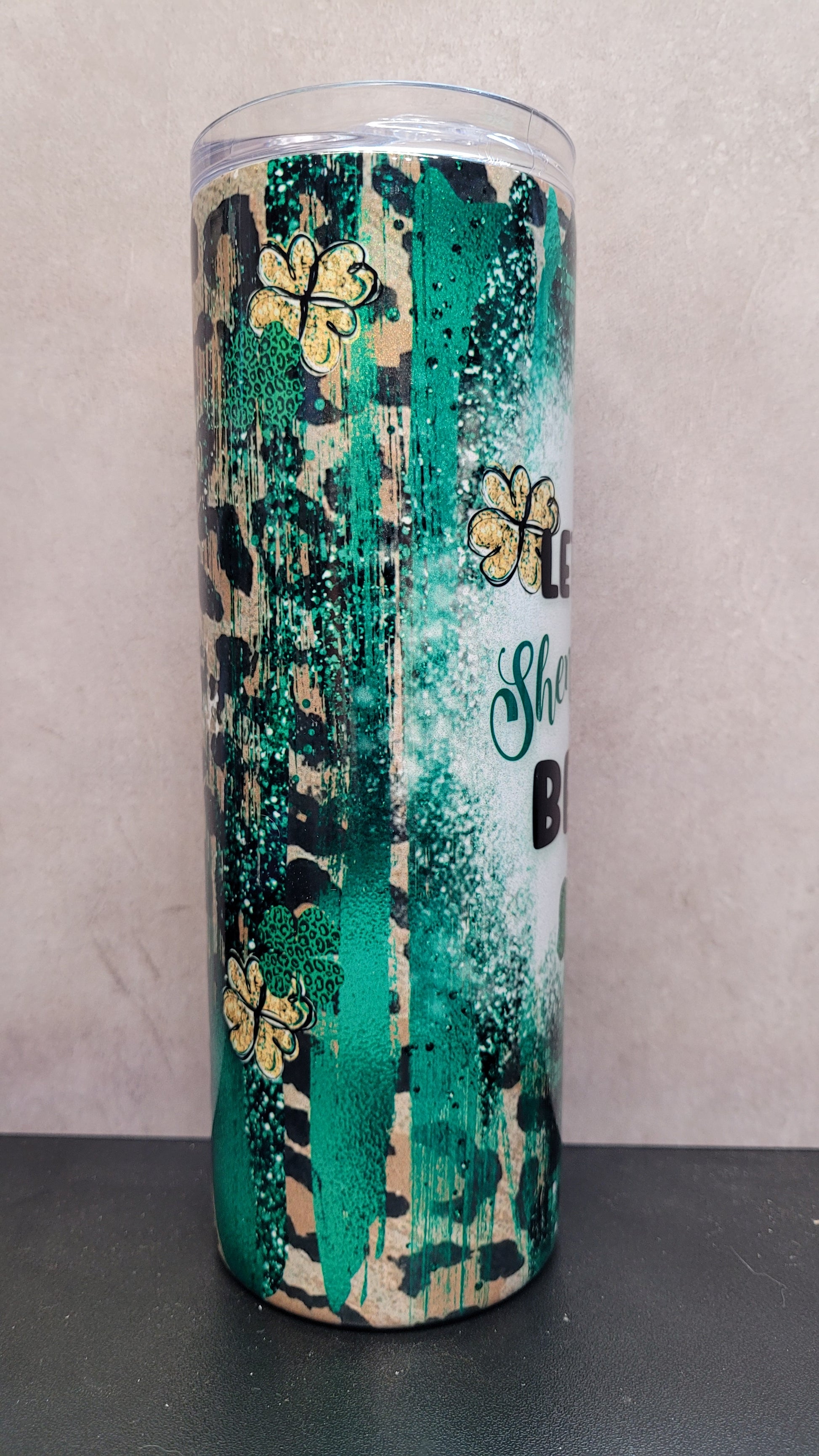 Let The Shenanigans Begin! This 20 oz tumbler features that phrase over a cheetah print background with splashes of Irish greens and luck charms.