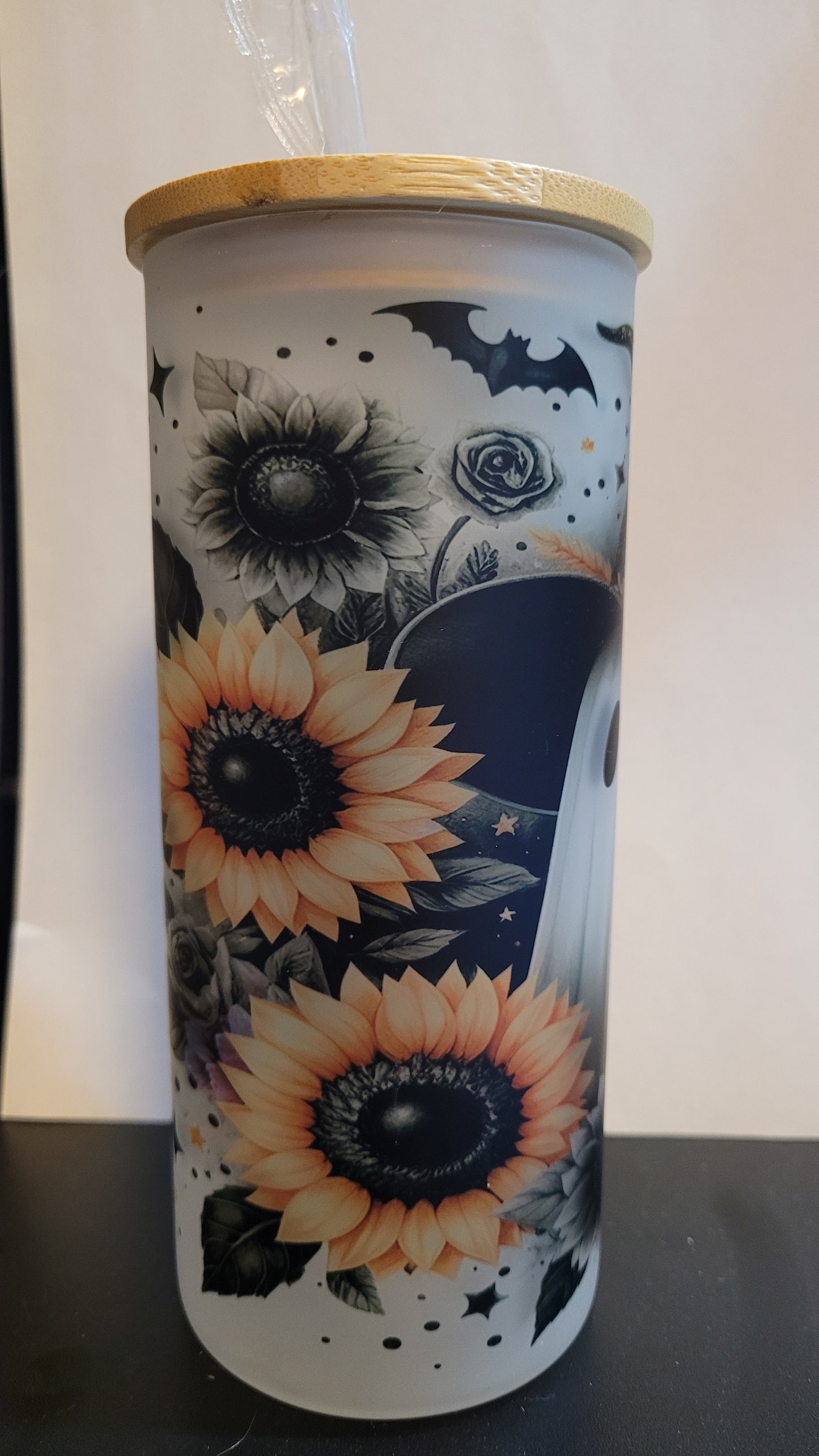 Not all ghosts are scary. Take this adorable Sunflower Ghost wearing a witch hat with a bat overhead and a carved pumpkin in the foreground. This image is sublimated onto a glass can tumbler and comes with a straw and bamboo lid.
