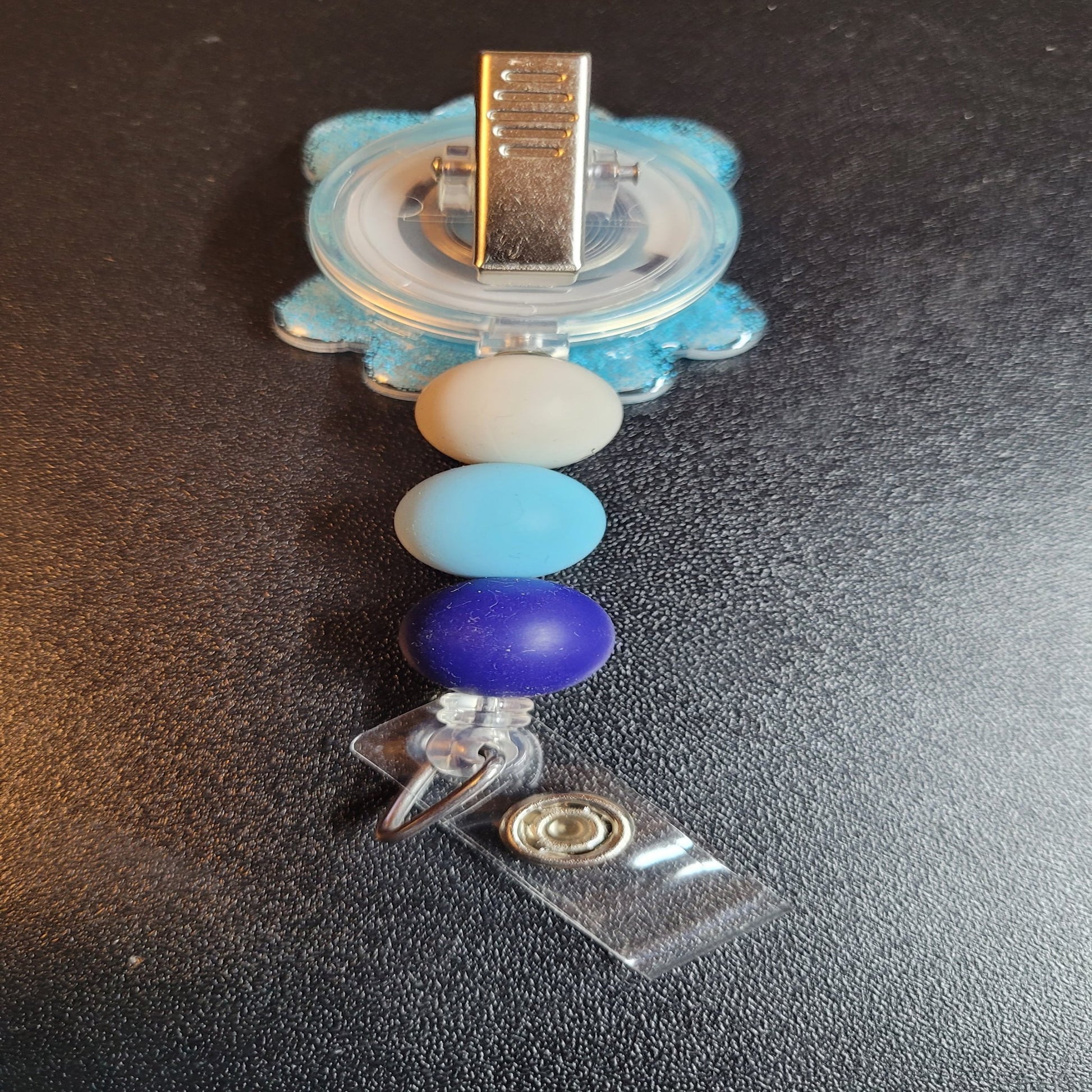 Introducing the Badge Reel Parka Polar Bear! Yes, even polar bears get cold and need to bundle up. Showcasing a blue puffy parka and a cozy knit cap, this charming polar bear is sure to bring a smile to your face. This stylish badge reel is finished with a blue glitter base and three carefully chosen silicone beads.