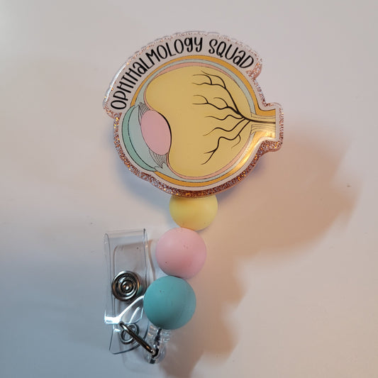Retractable badge holder with colorful beads and 'Ophthalmology Squad' design on a light background