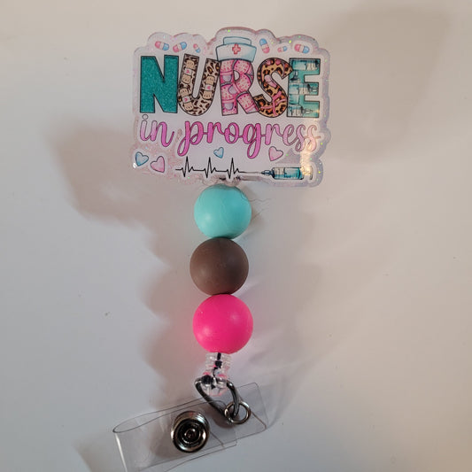 Badge holder with colorful beads and 'Nurse in progress' sign on a white background