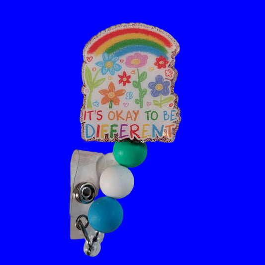 Colorful badge holder with rainbow, flowers, and 'It's Okay to Be Different' text on a white background.