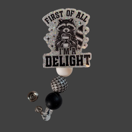 Badge holder with raccoon design and text 'First of all I'm a Delight' on a light background