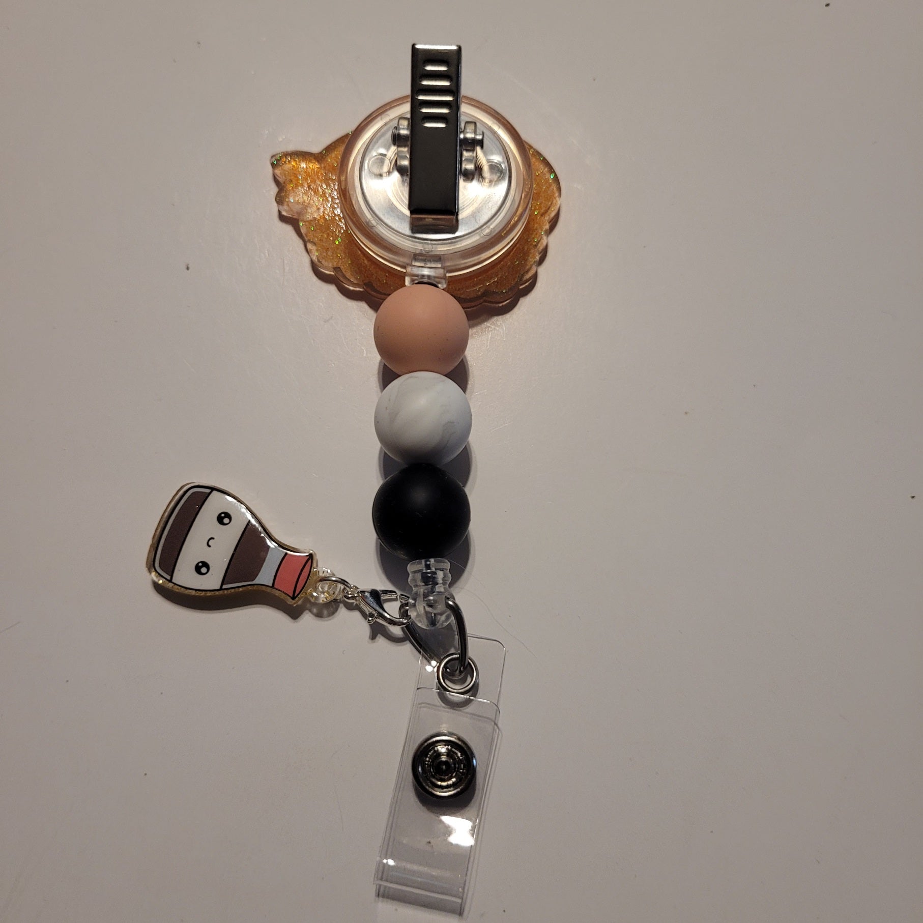 Retractable badge holder with colorful beads and a character charm on a white background