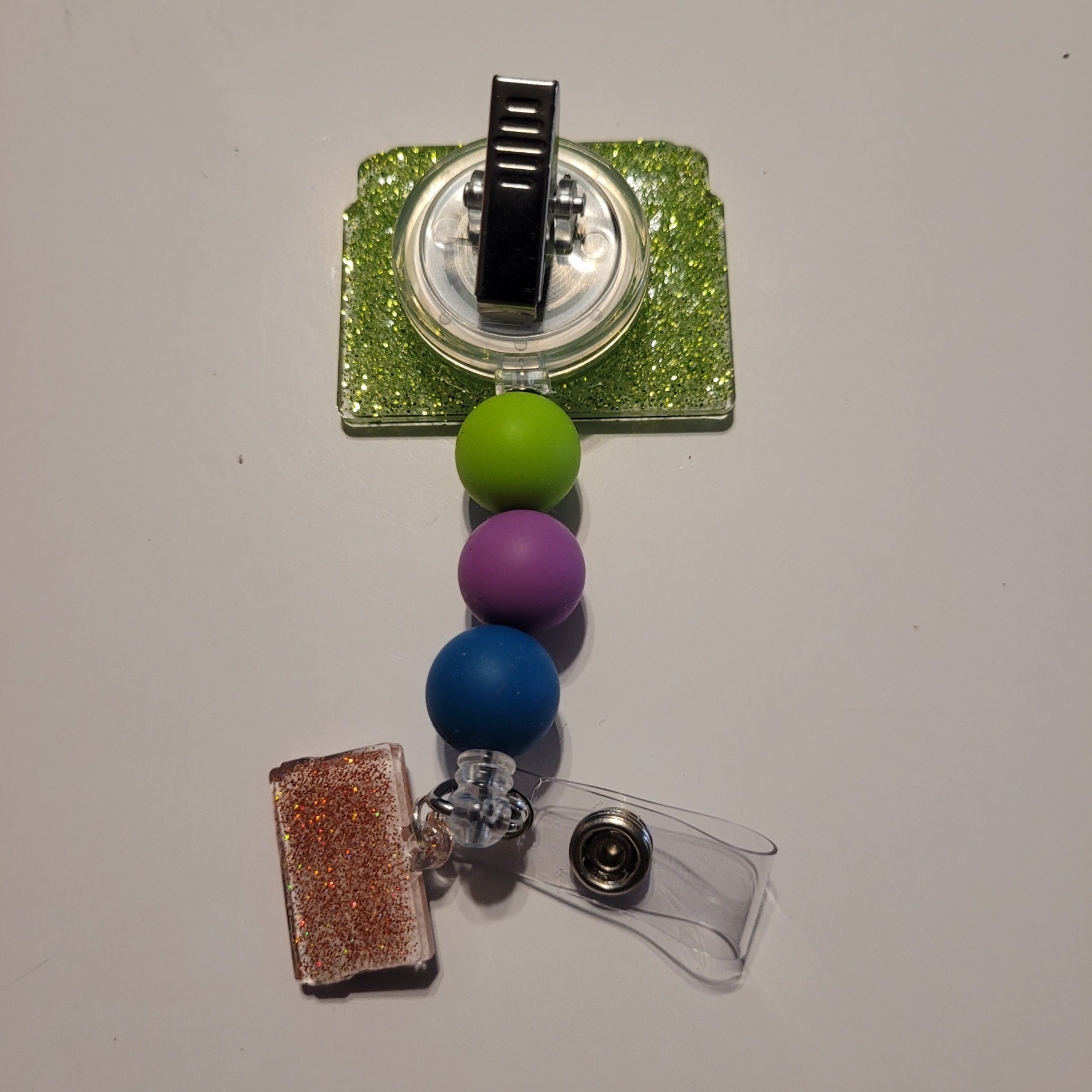Badge holder with colorful beads and glittery accents on a plain background