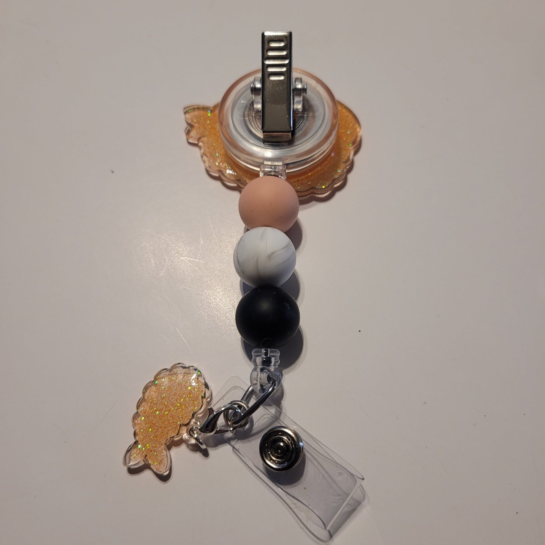 Retractable badge holder with decorative elements on a white background